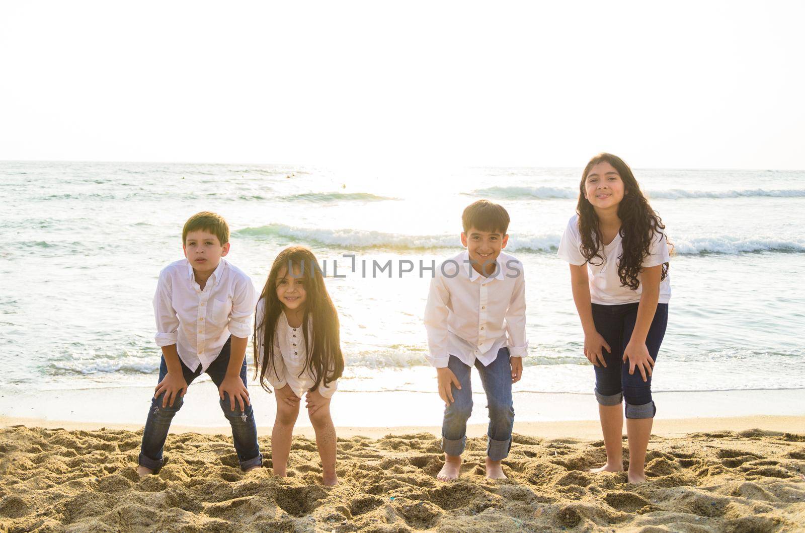 Group of children playing at the edge of the sea in sunlight.