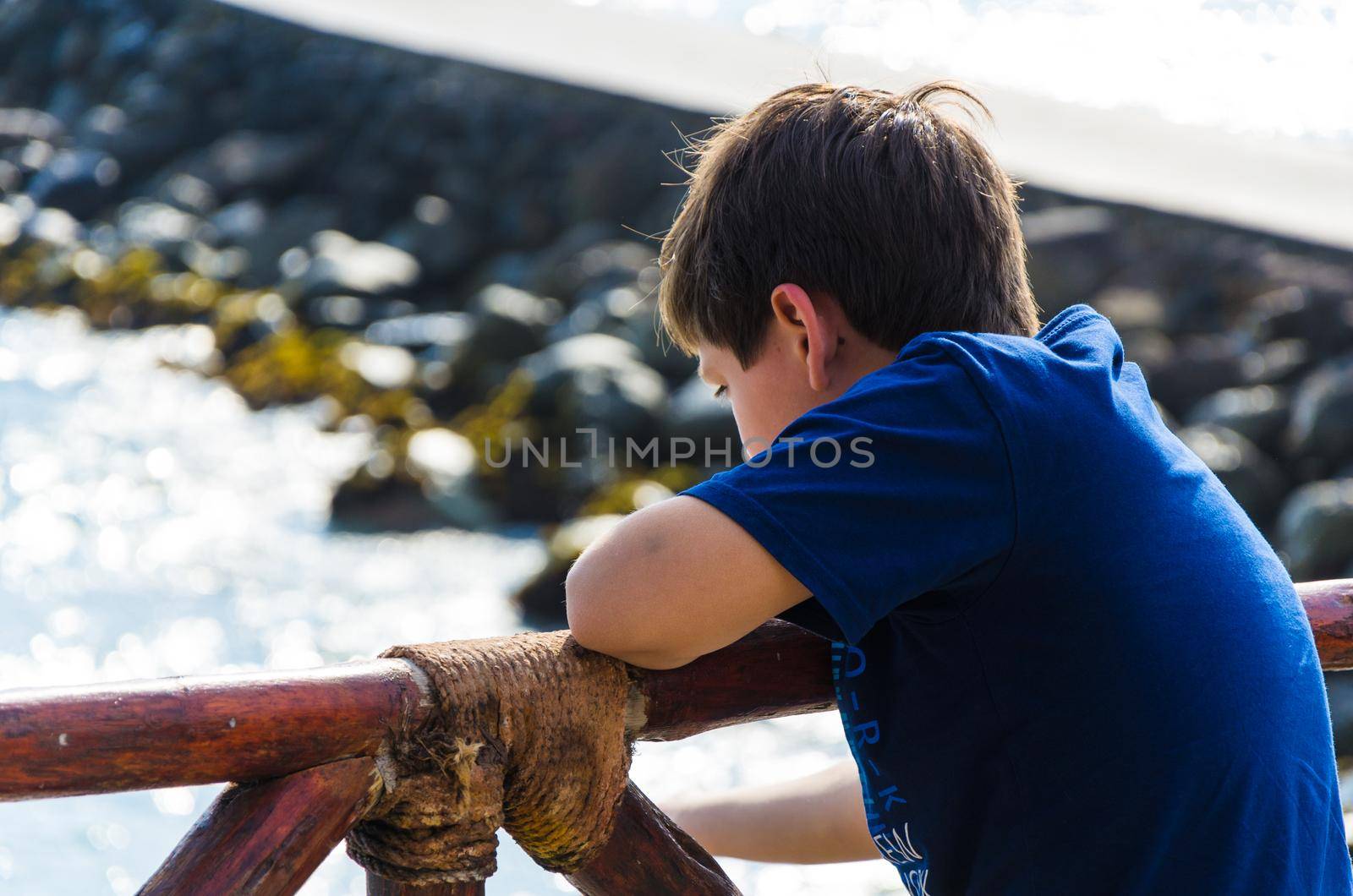 A boy looking at the sea with his back to the camera. Child looking at the sea on the beach