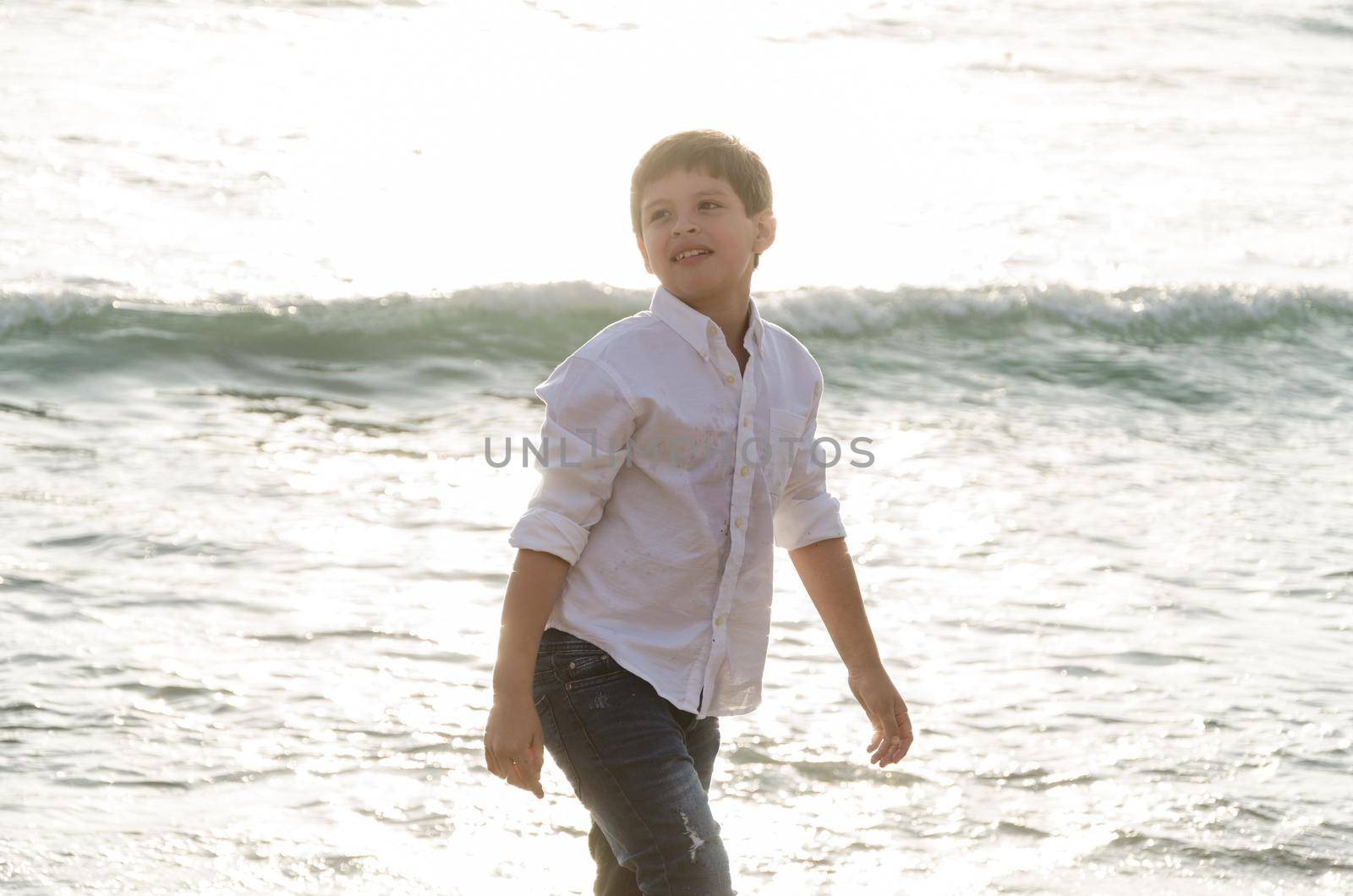 Portrait of a happy little boy playing on the beach in summer