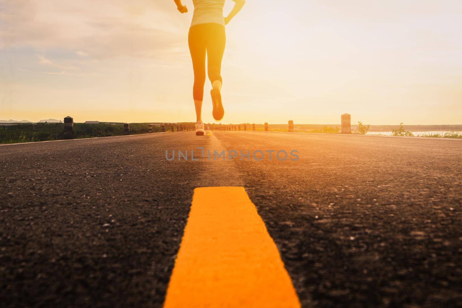 Athlete running on the road trail in sunset training for marathon and fitness. motion blur of woman exercising outdoors by psodaz