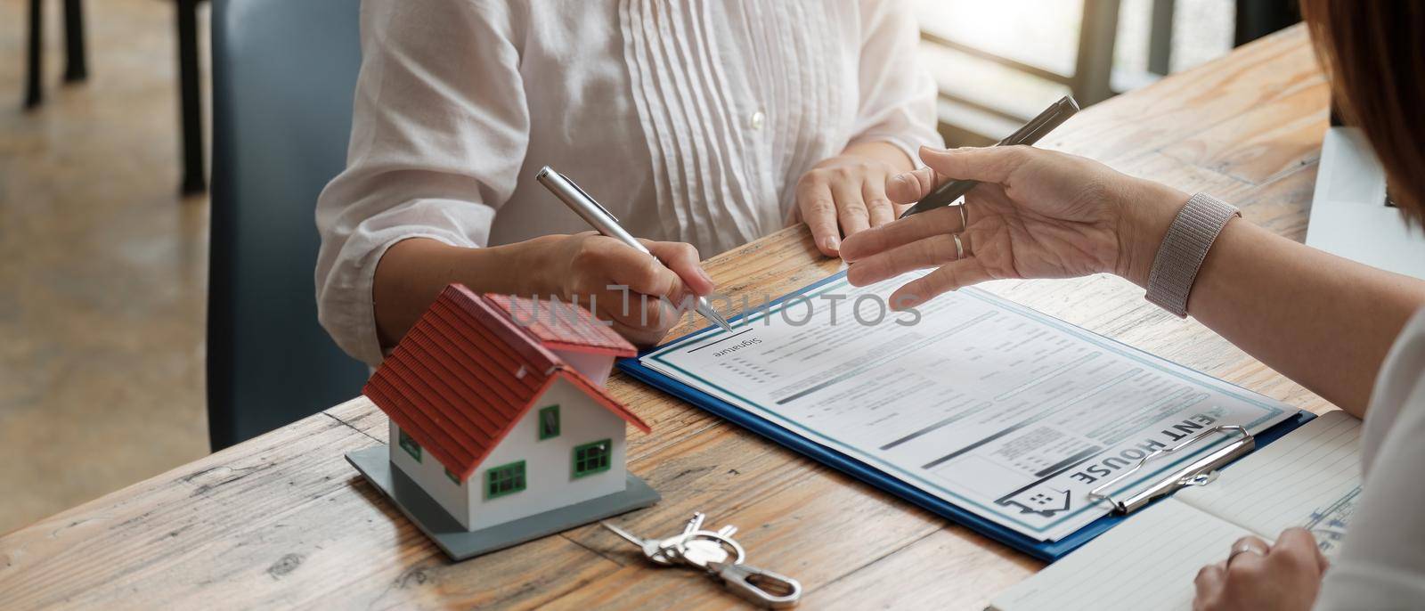 close up view hands of businessman signing leasing home documents and have a apartment keys on paperwork by nateemee