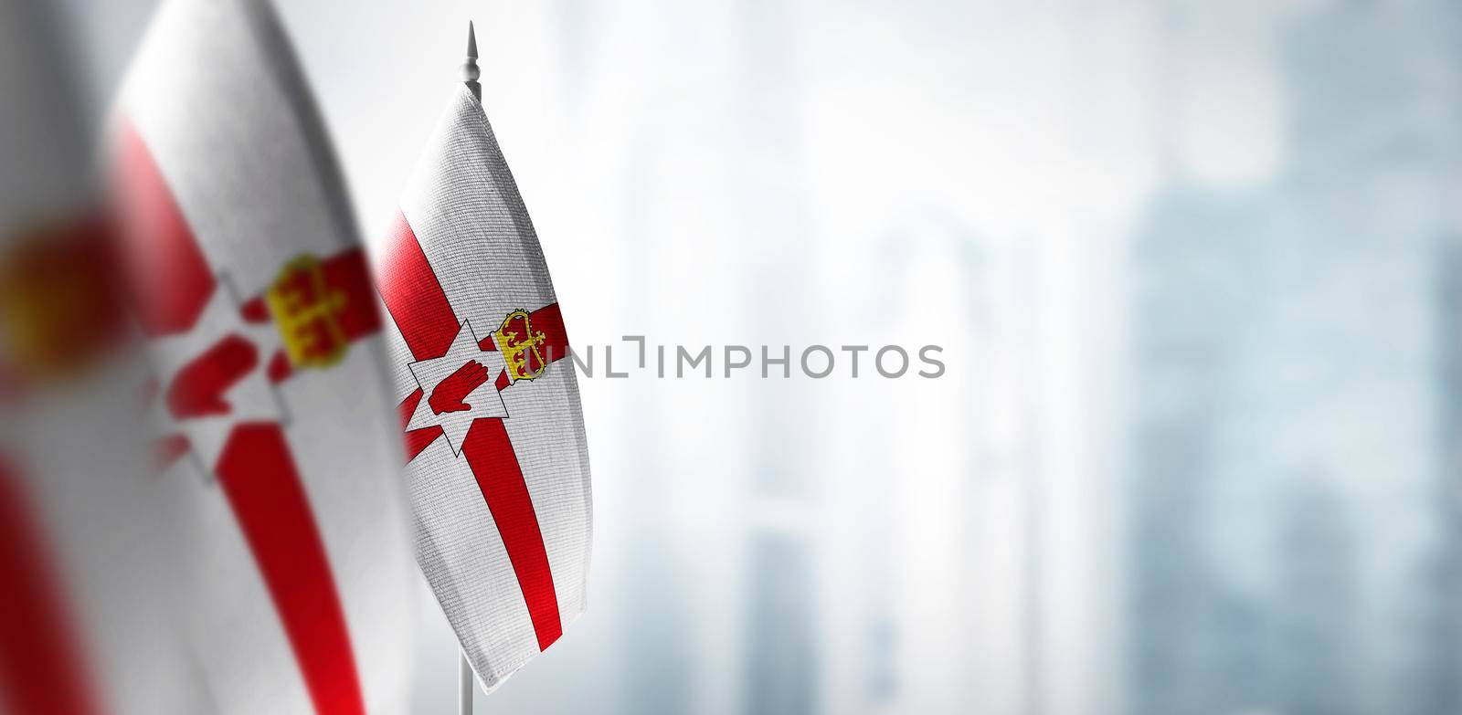 Small flags of Northern Ireland on a blurry background of the city.