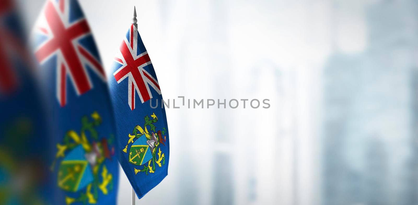 Small flags of Pitcairn Islands on a blurry background of the city.