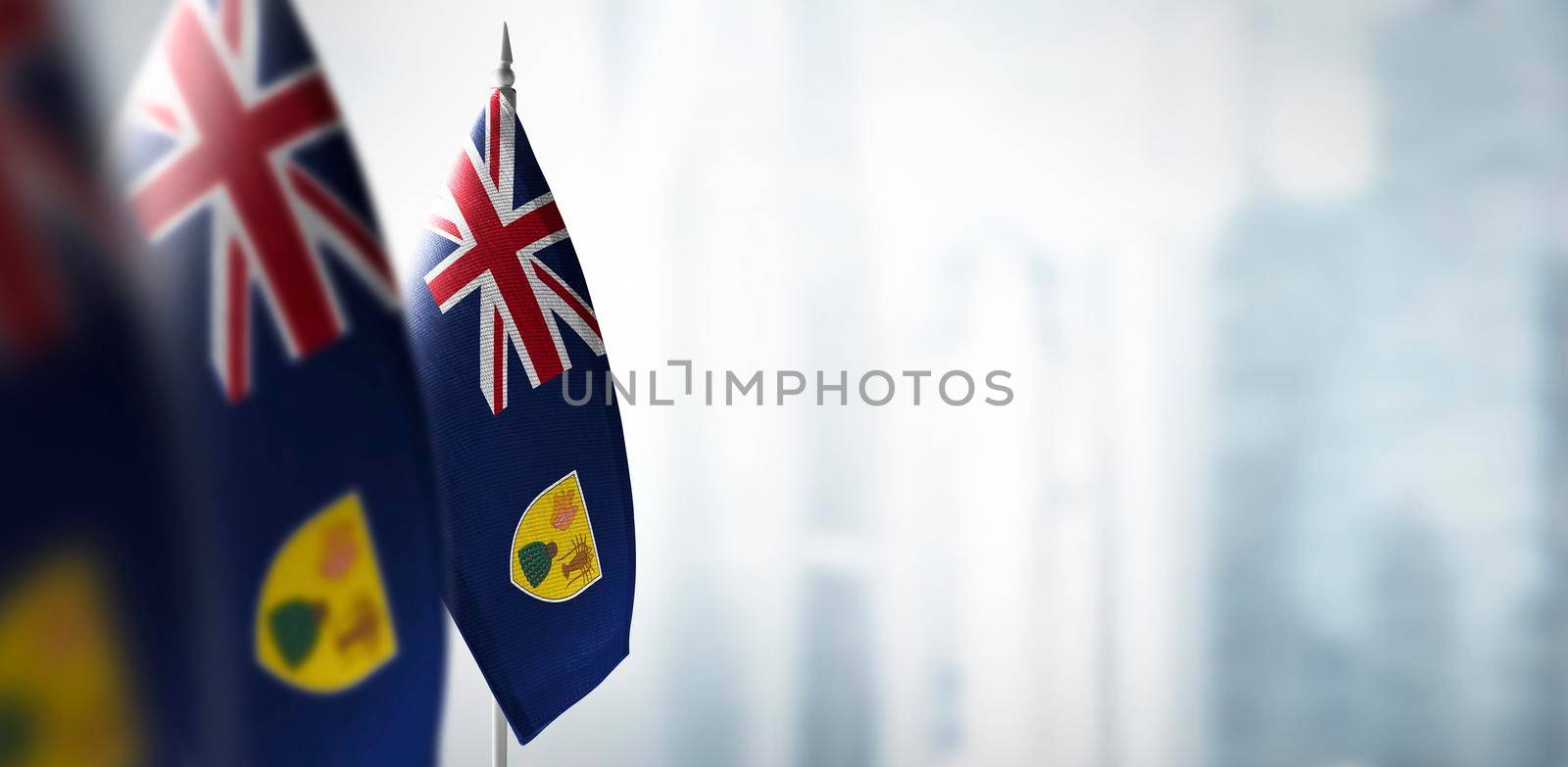 Small flags of Turks and Caicos Islands on a blurry background of the city by butenkow