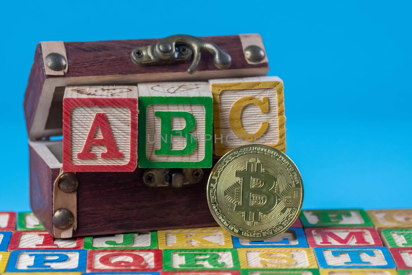 Bitcoin crytocurrency and alphabet wooden block near treasure chest