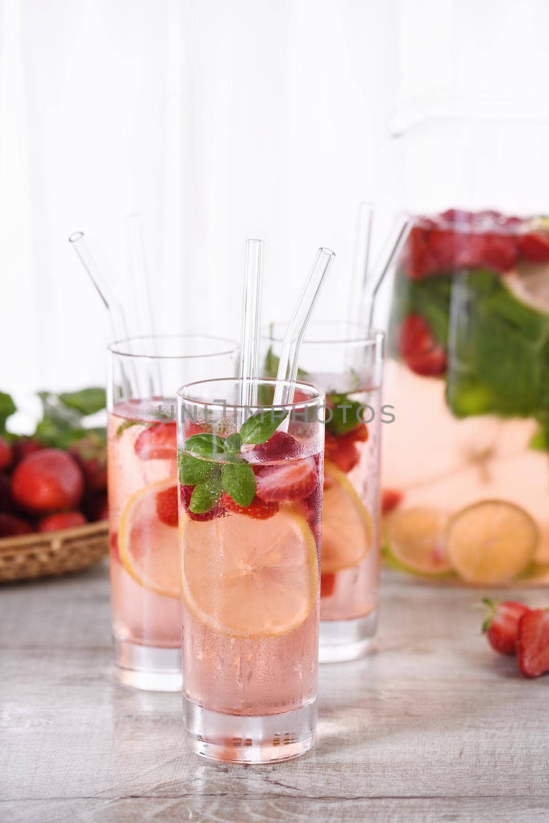 Summer strawberry cocktail or lemonade with basil. Cold refreshing organic soft drink with ripe berries in a glass