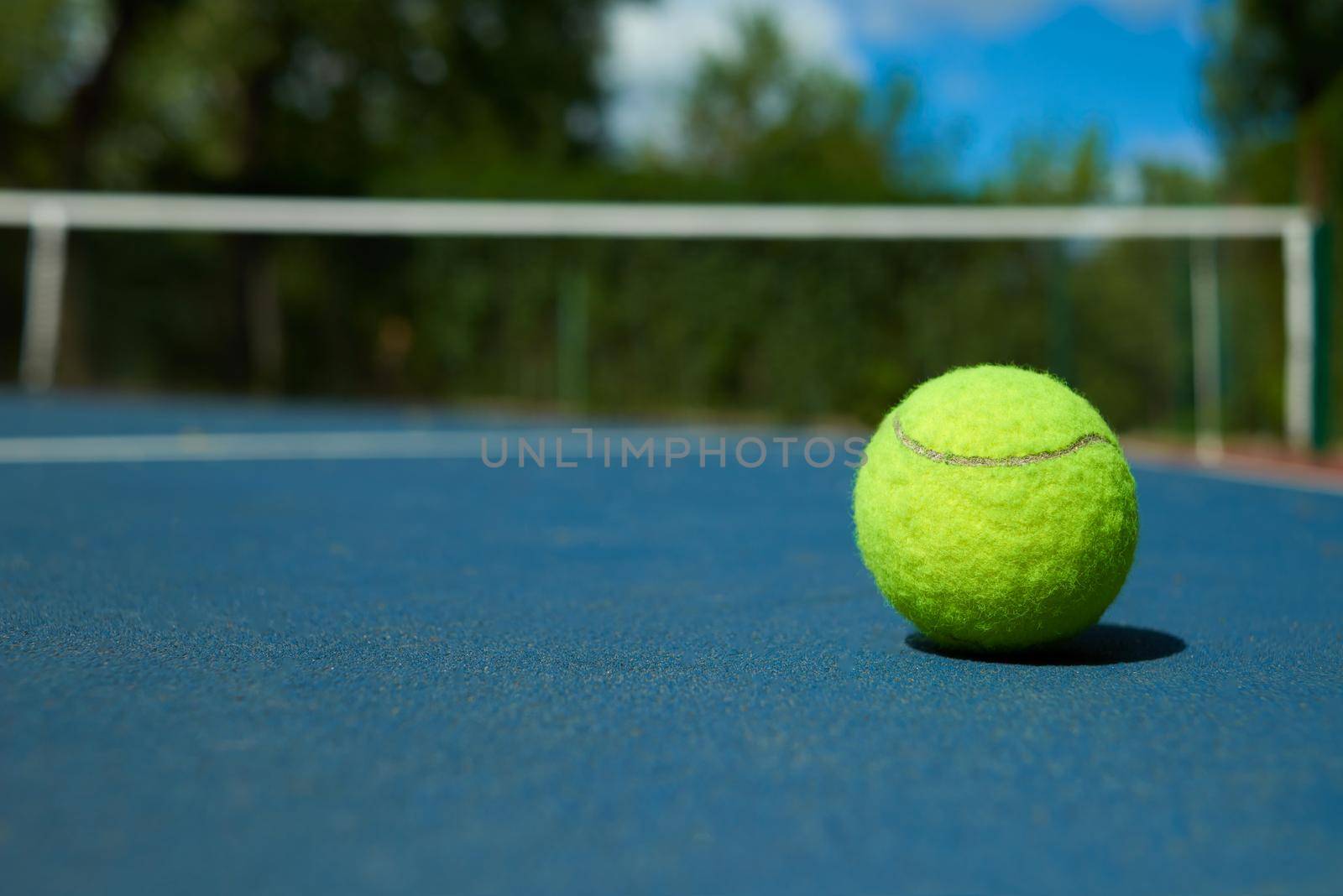 Yellow tennis ball on blue carpet of opened court. by SerhiiBobyk