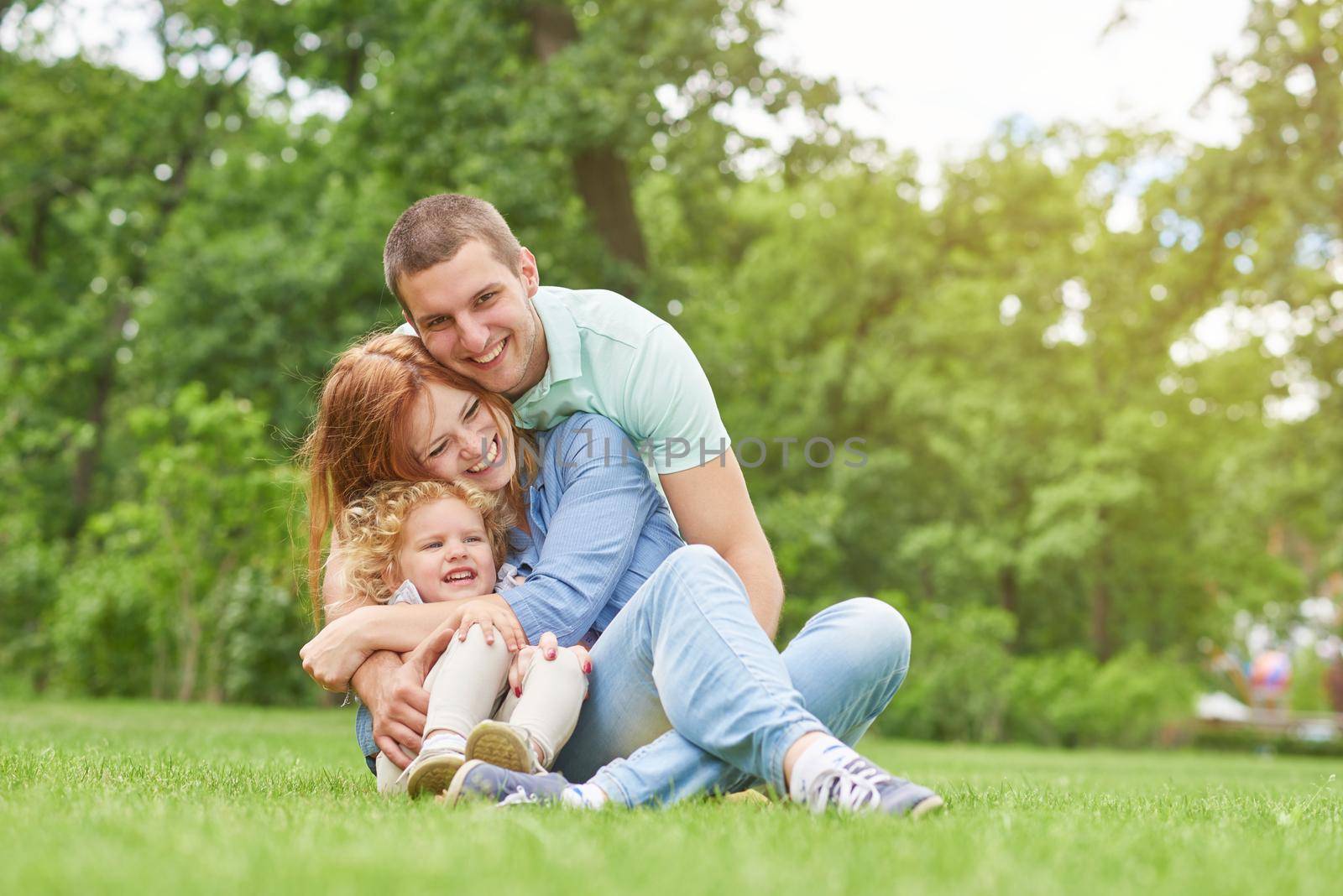 Shot of a happy young loving family having fun outdoors sitting on the grass at the park on a warm summer day hugging and cuddling copyspace parents love couples children kids daughter father mother.