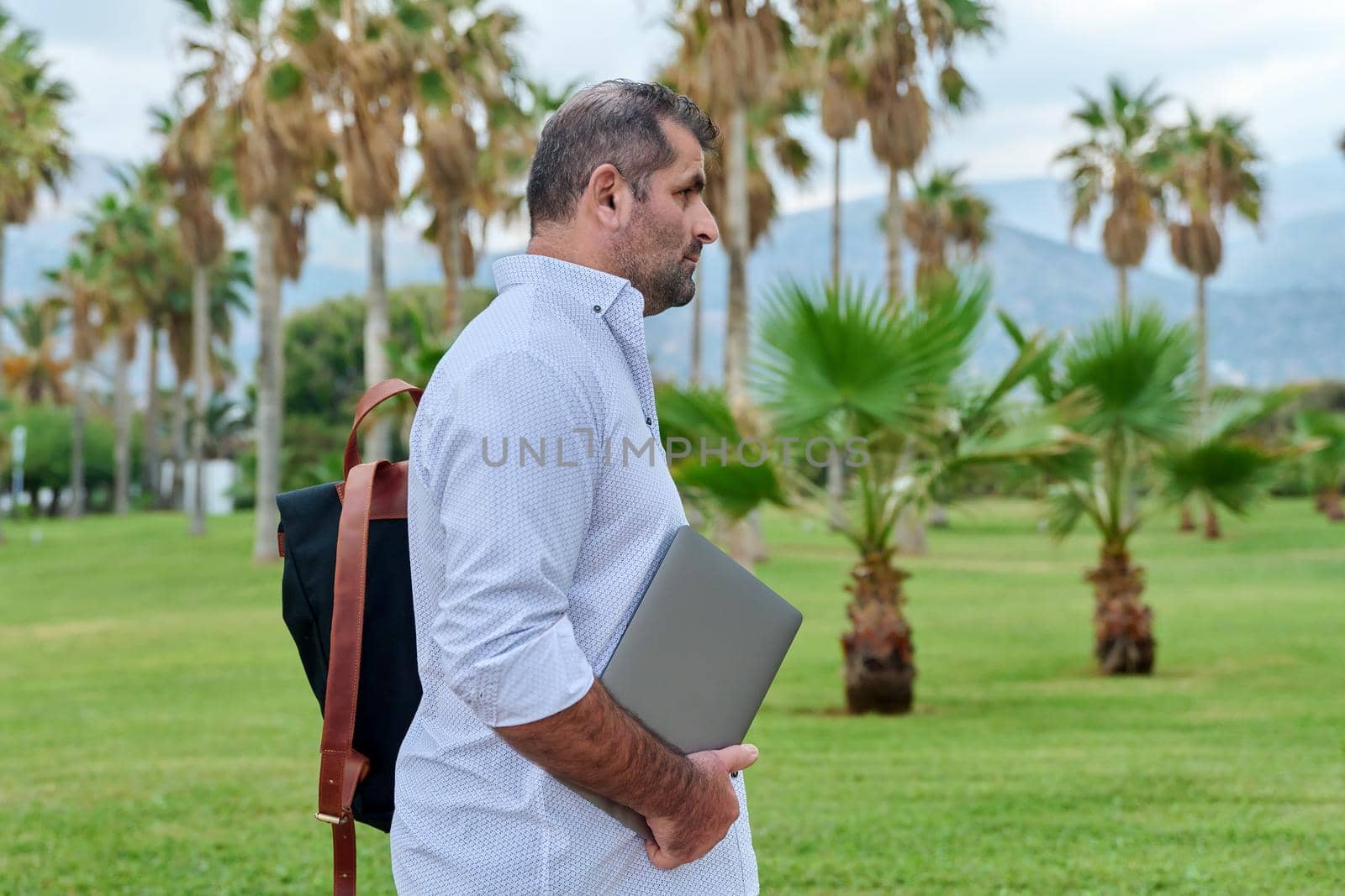 Portrait of serious confident mature man with laptop outdoors by VH-studio