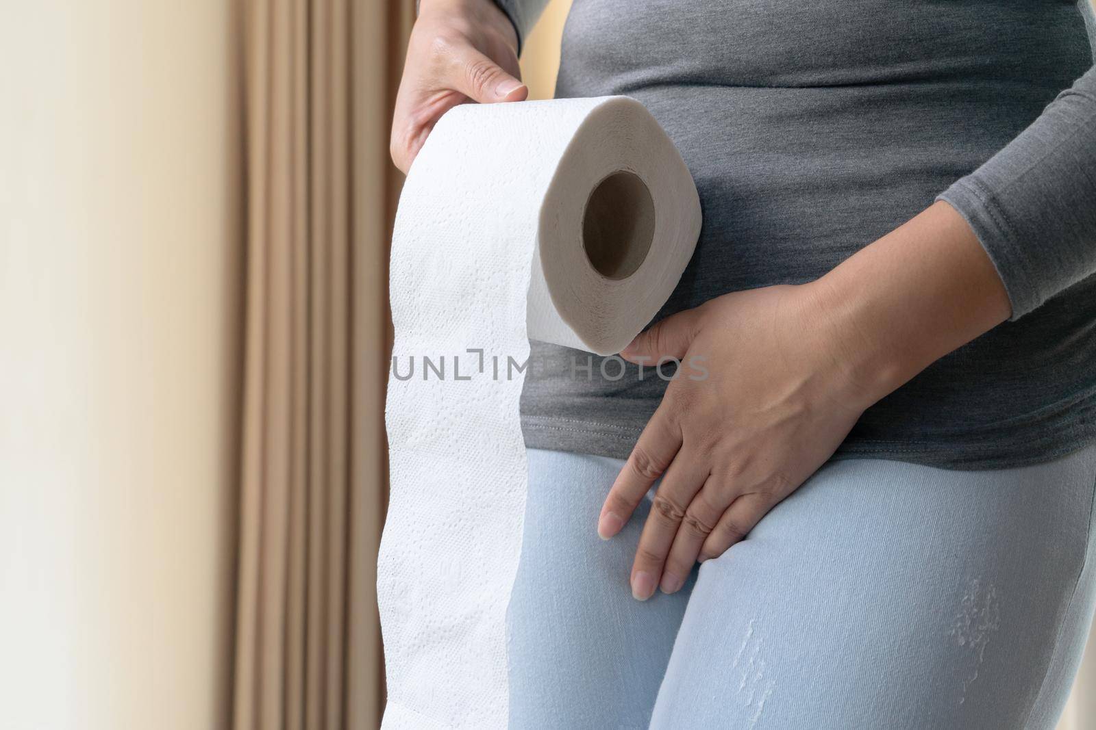 Disorder, Diarrhea, incontinence. Healthcare concept. Woman hand holding her crotch lower abdomen and tissue or toilet paper roll.