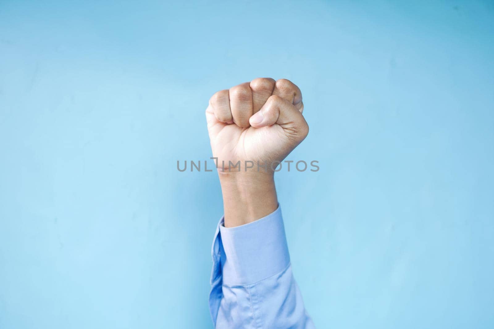 hands clenched power strength isolated on blue.