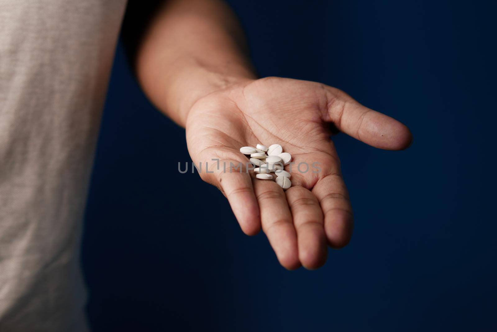 man's hand with pills spilled out of the container .