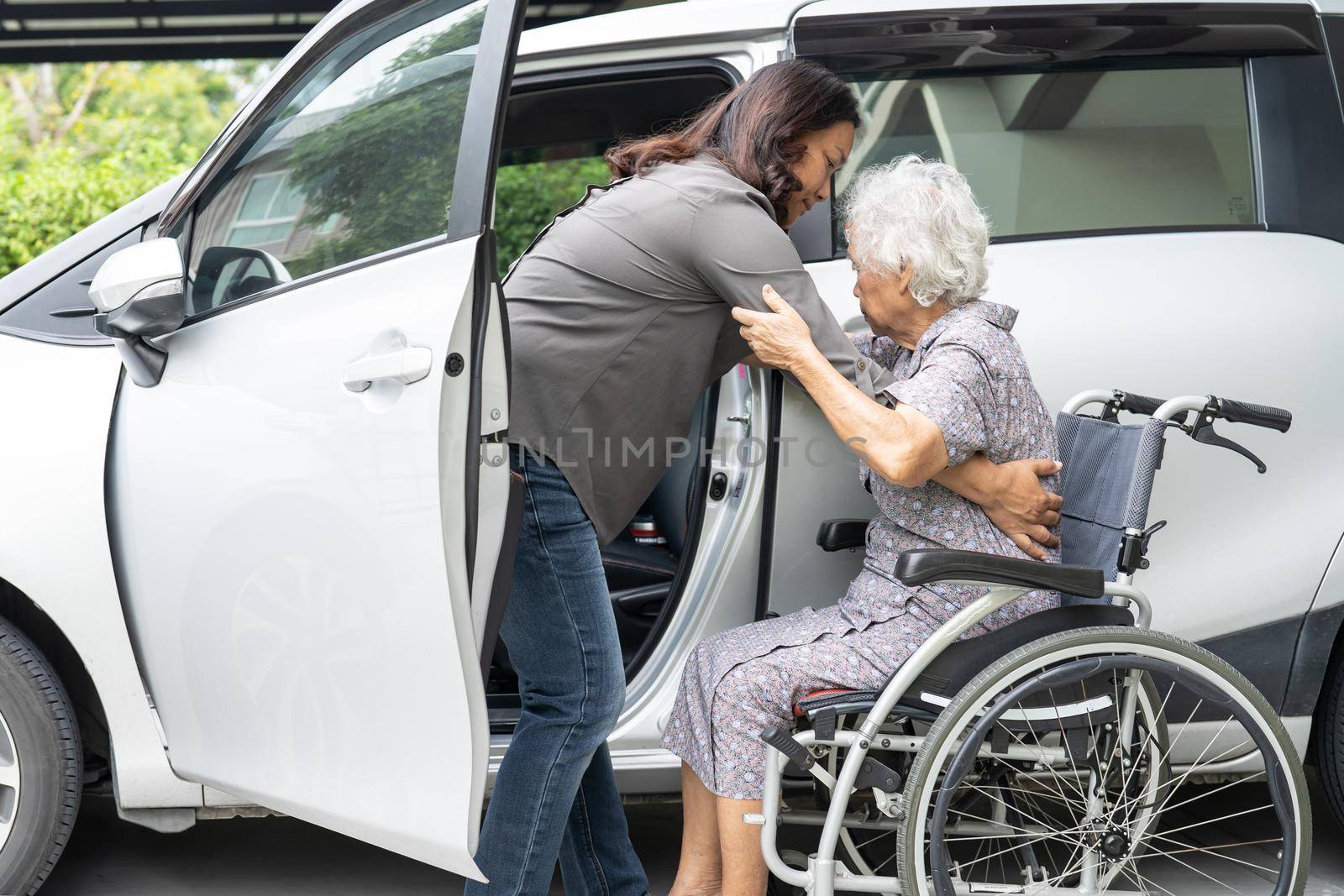 Help and support asian senior or elderly old lady woman patient sitting on wheelchair prepare get to her car, healthy strong medical concept.