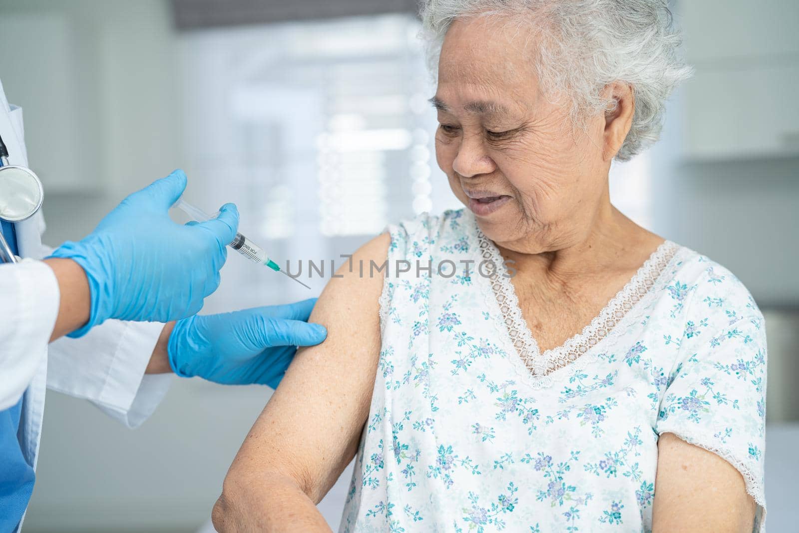 Elderly Asian senior woman wearing face mask getting covid-19 or coronavirus vaccine by doctor make injection. by pamai