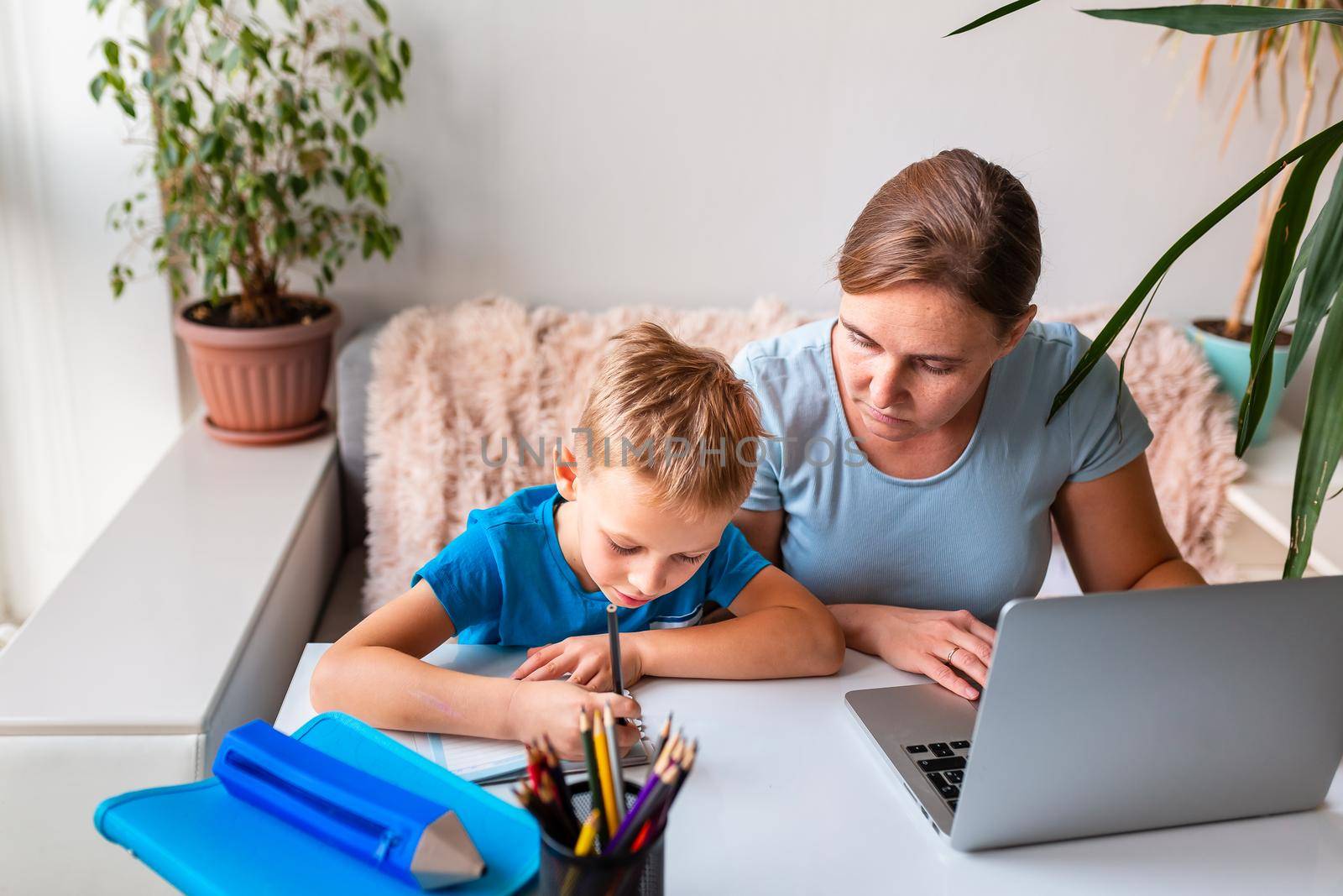 Mother with kid trying to work from home during quarantine. Stay at home, work from home concept during coronavirus pandemic