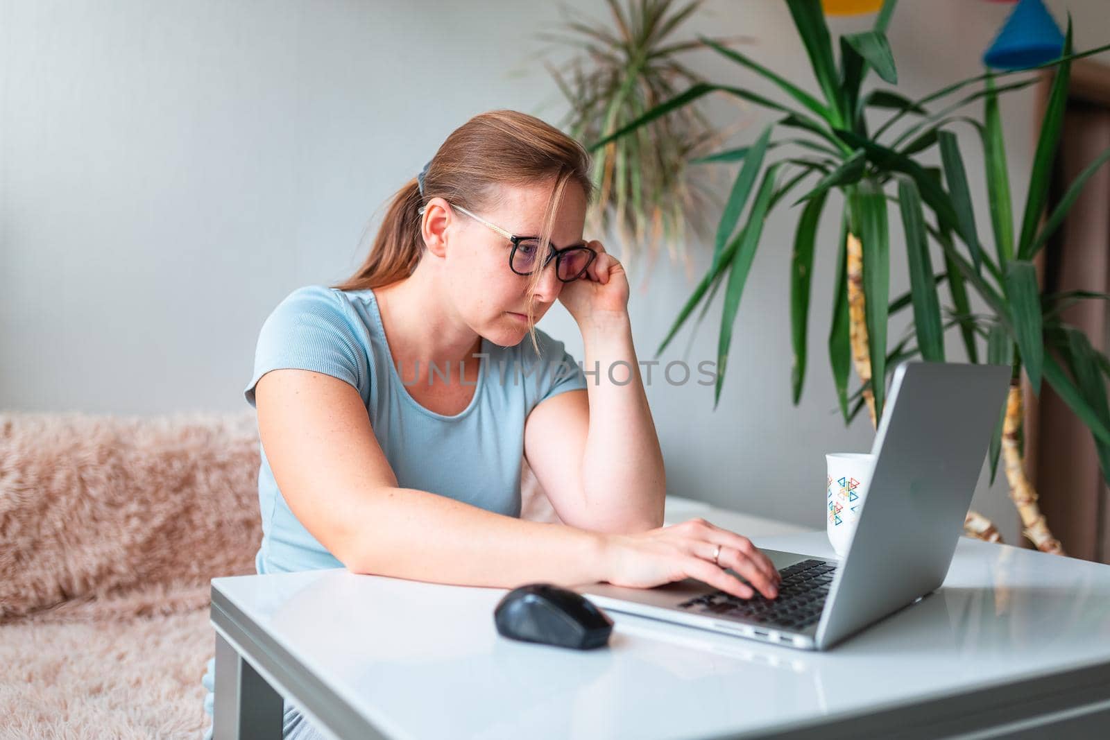 Middle age woman sitting at the table at home working using computer laptop. Work from home and stay at home during coronovirus pandemic concept
