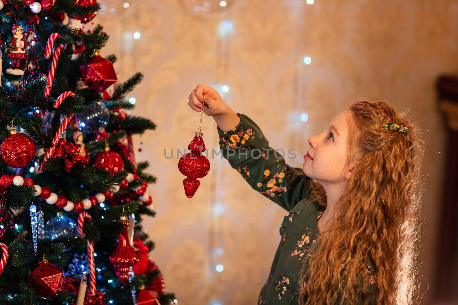 Happy little girl decorating the Christmas tree at Christmas eve. Christmas morning, christmas mood concept