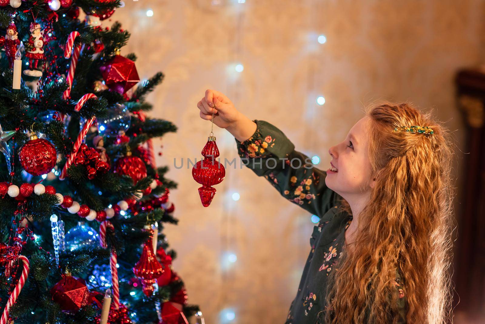 Happy little girl decorating the Christmas tree at Christmas eve. Christmas morning, christmas mood concept