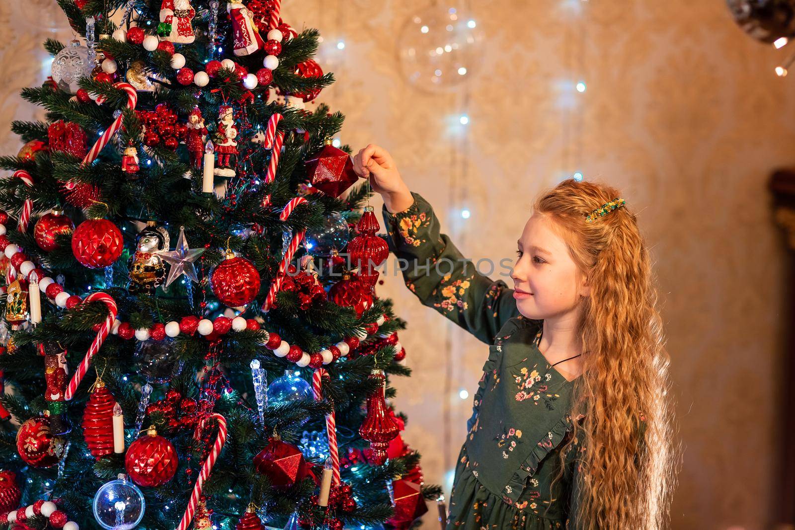 Happy little girl decorating the Christmas tree at Christmas eve. Christmas morning, christmas mood concept