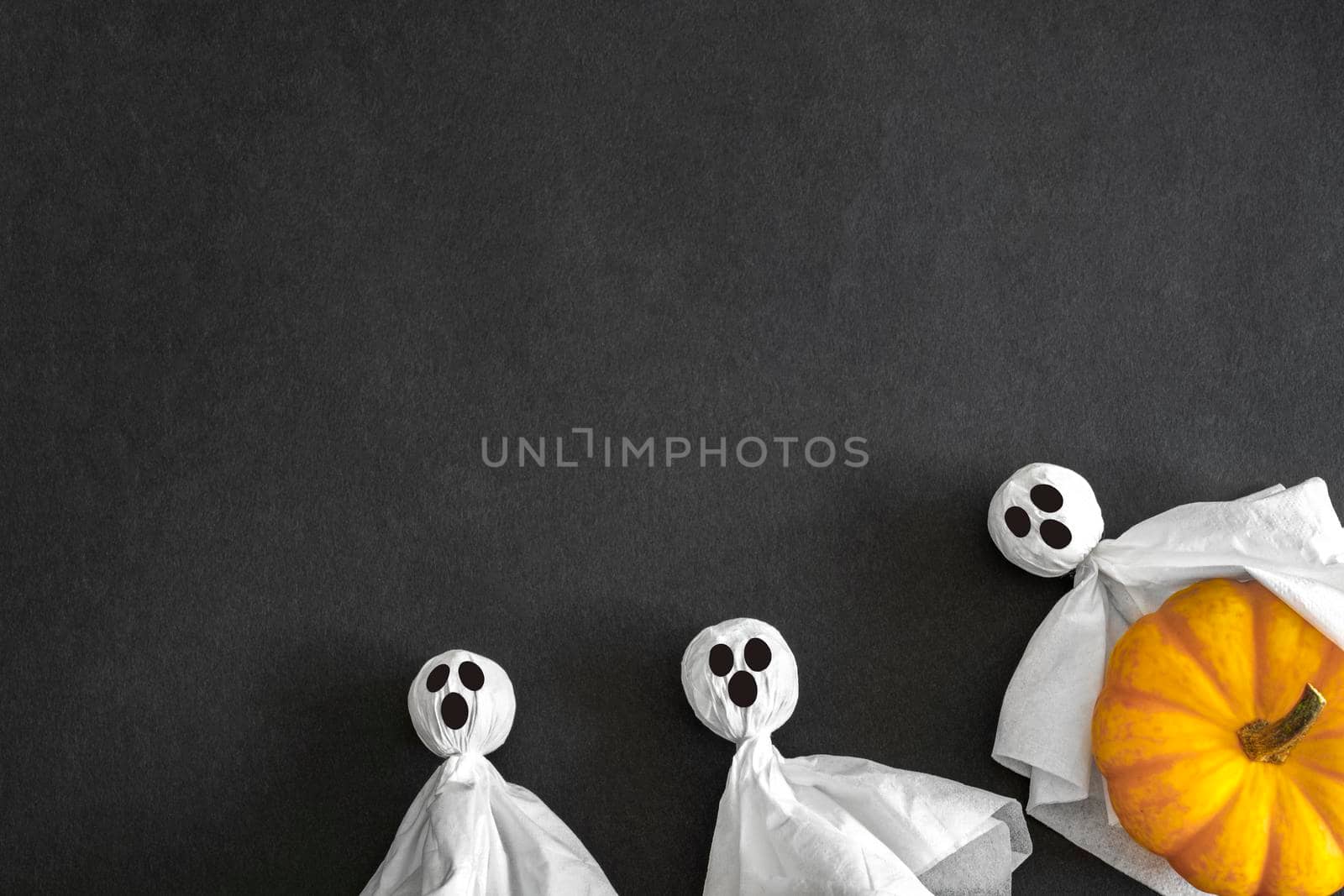Two ghosts and pumpkin, black background, top view. Copy space. Halloween Concept