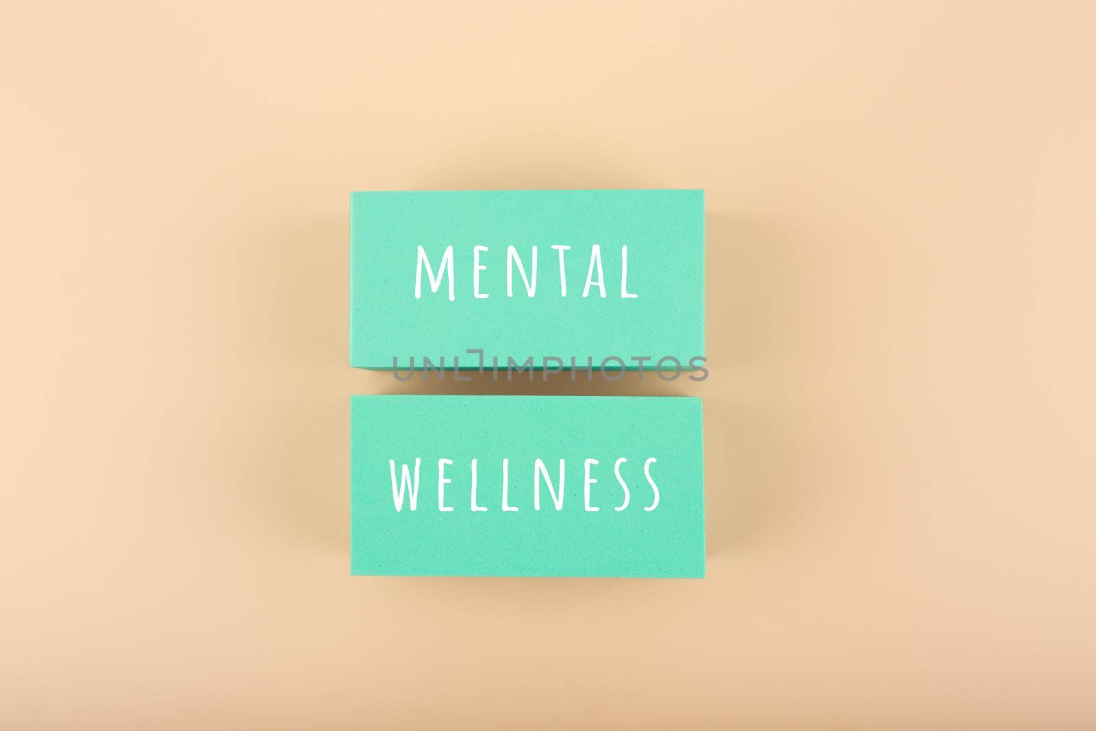 Mental wellness text written on aqua blue toy blocks on bright beige background by Senorina_Irina