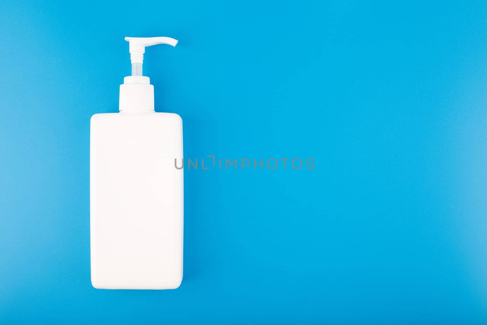 Hand sanitizer in white tall plastic bottle with dispenser isolated on blue background with copy space. Concept of safety and hygiene