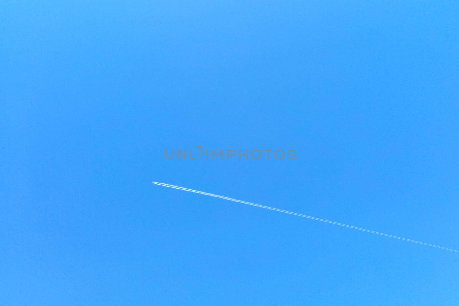 Out of focus, a plane flies against the blue sky. by kip02kas