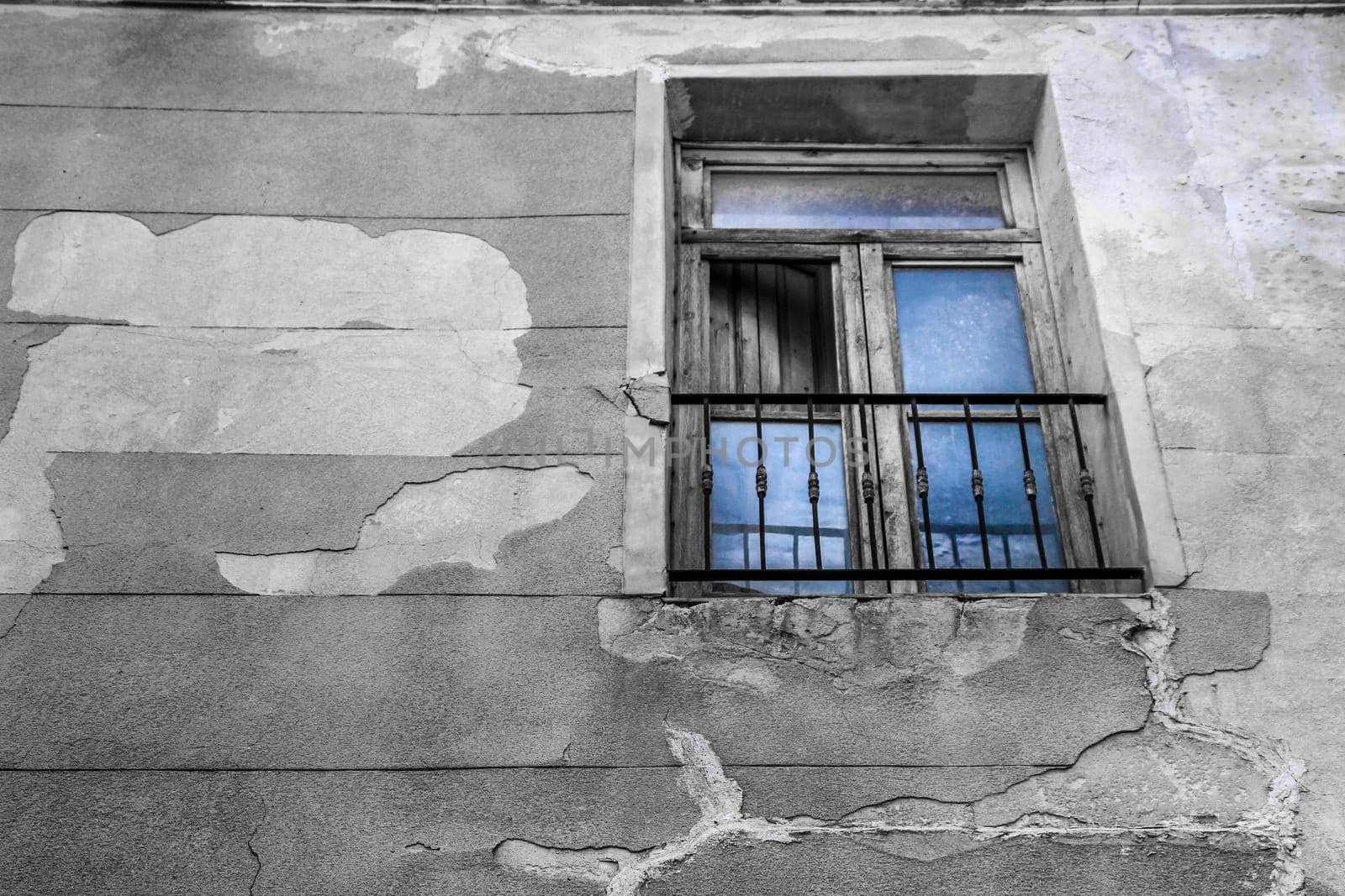 Old house facade with wooden damaged window in Novelda village, Valencia community, Spain.