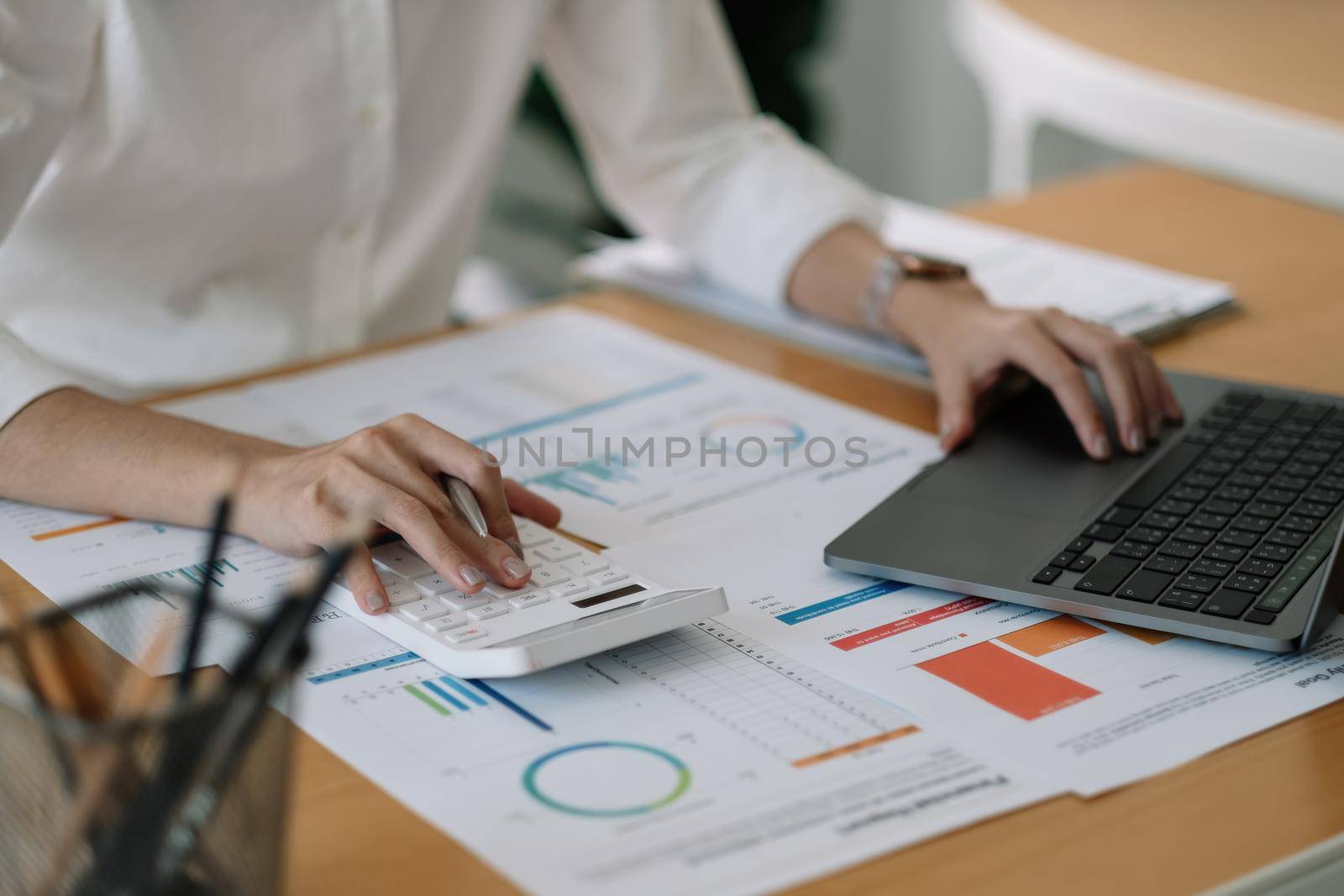 Woman accountant using calculator and laptop computer for financial budget and loan paper in office.