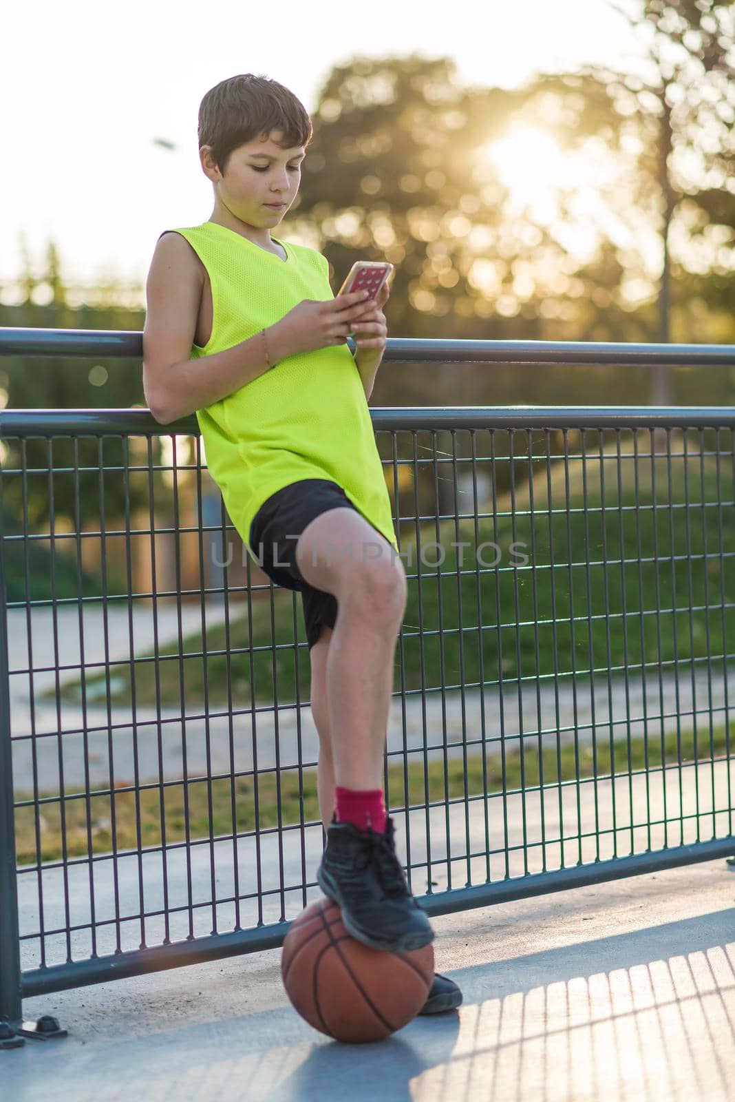 A Young male using a phone outdoors at sunset