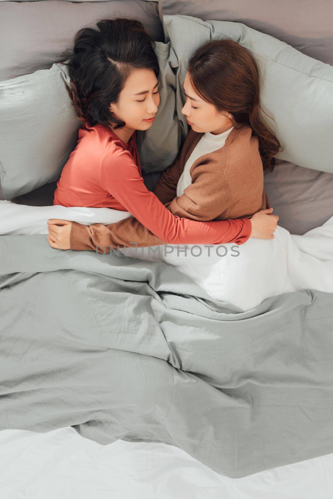 Two pretty best friends forever girlfriend talk, hug and laugh together on bed at cozy home relation fall in love