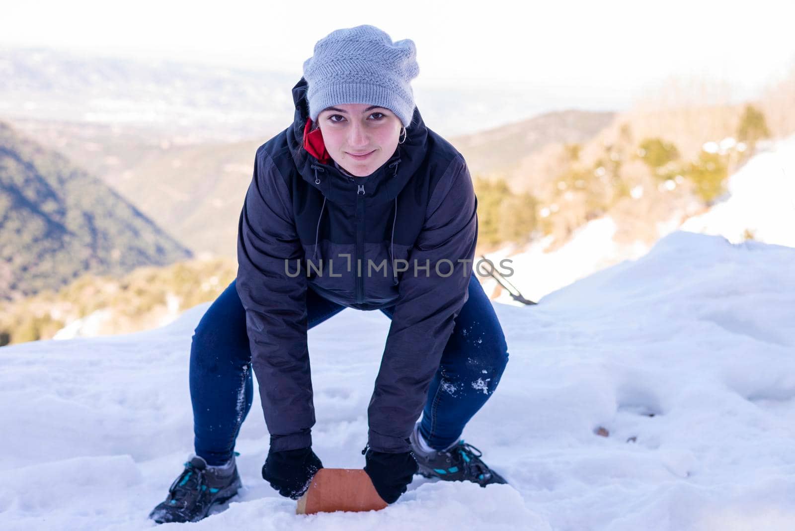 Young smiling woman in snowy mountains at sunset in winter.