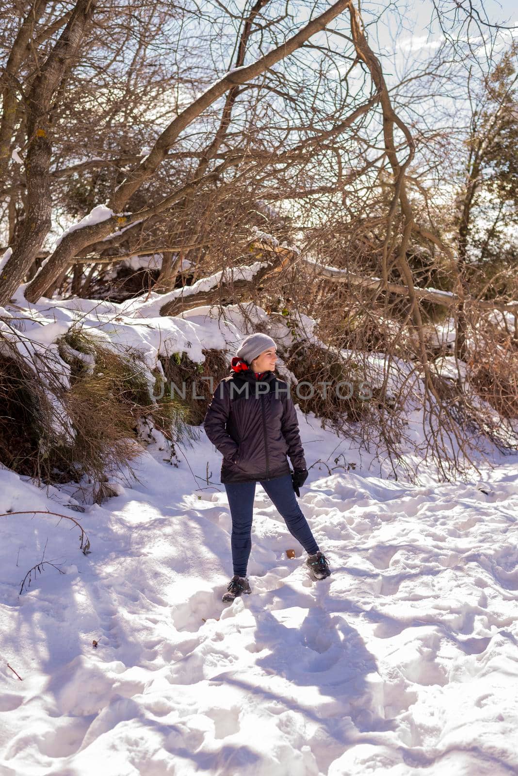 Young smiling woman in snowy mountains at sunset in winter.