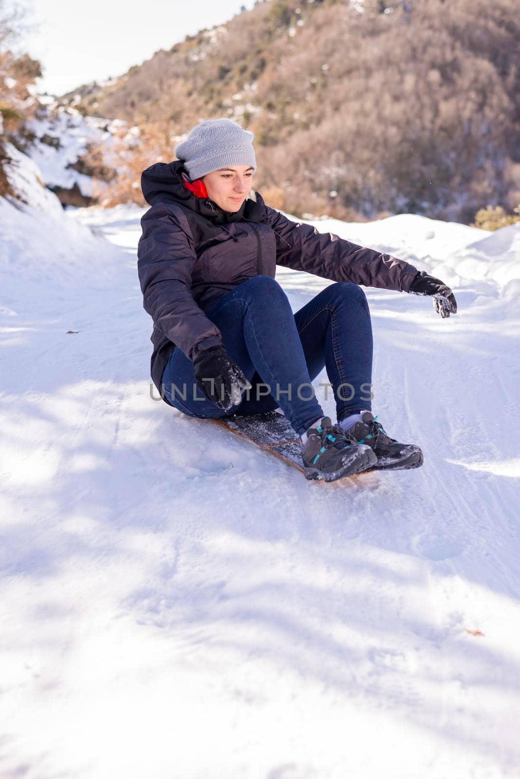 portrait of pretty young woman sliding down hill on snow saucer sled outdoors in winter. by raferto1973