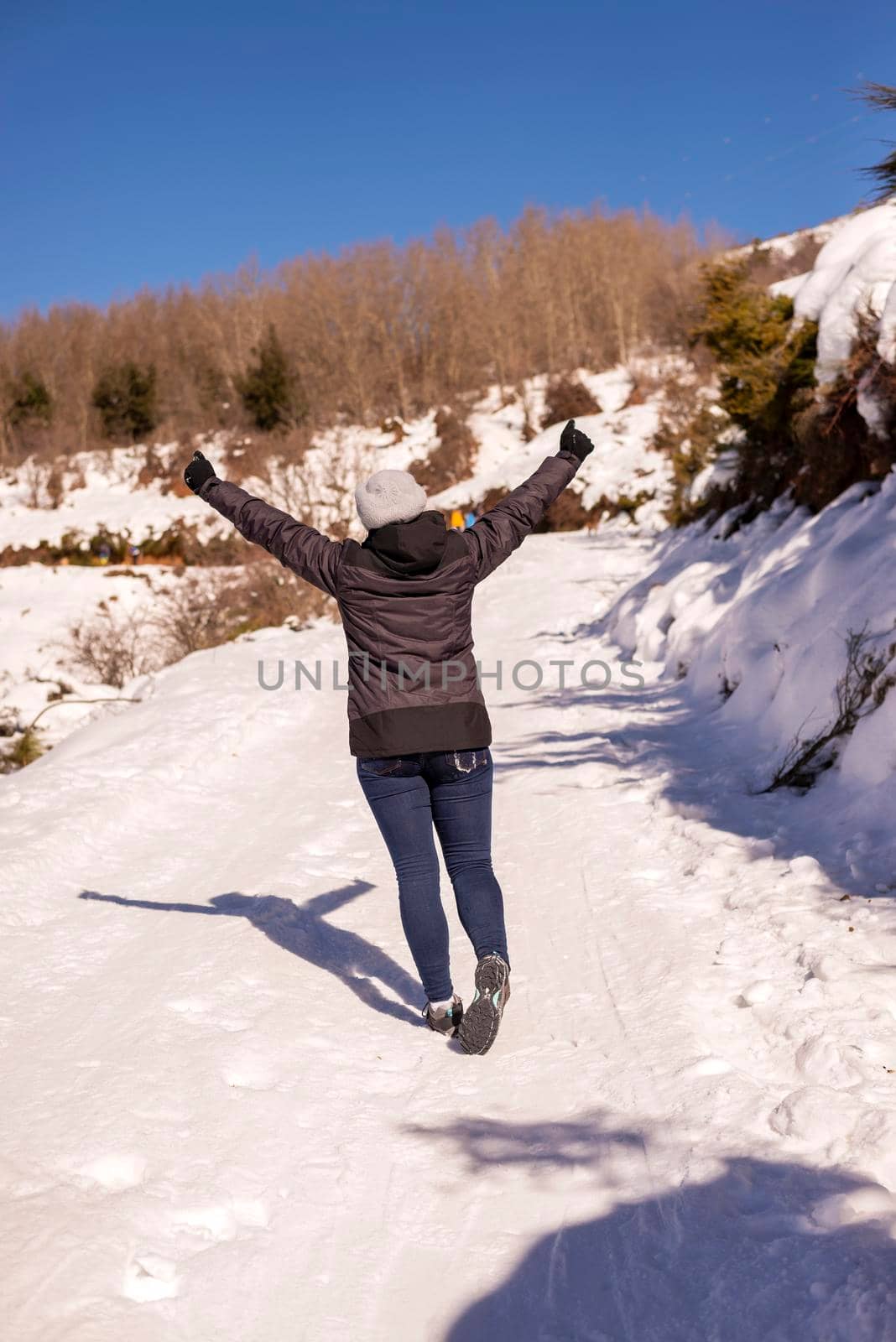 A Young traveler woman standing on snow mountain with arms raised