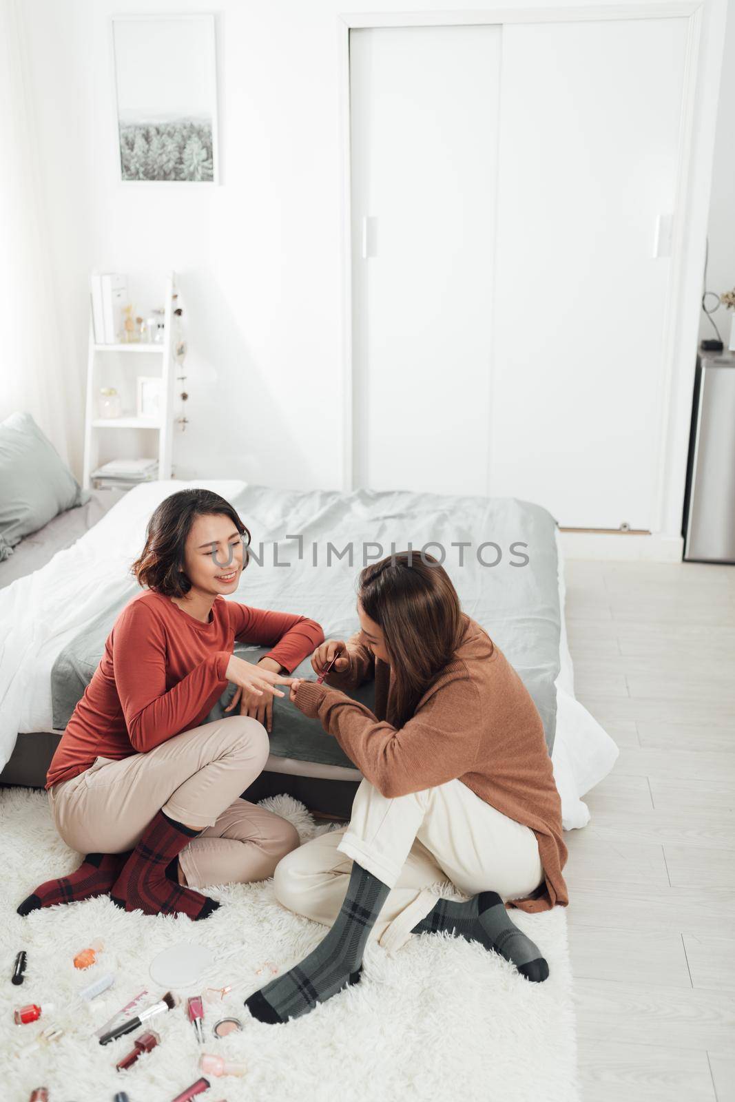 Women applying nail polish at home by makidotvn