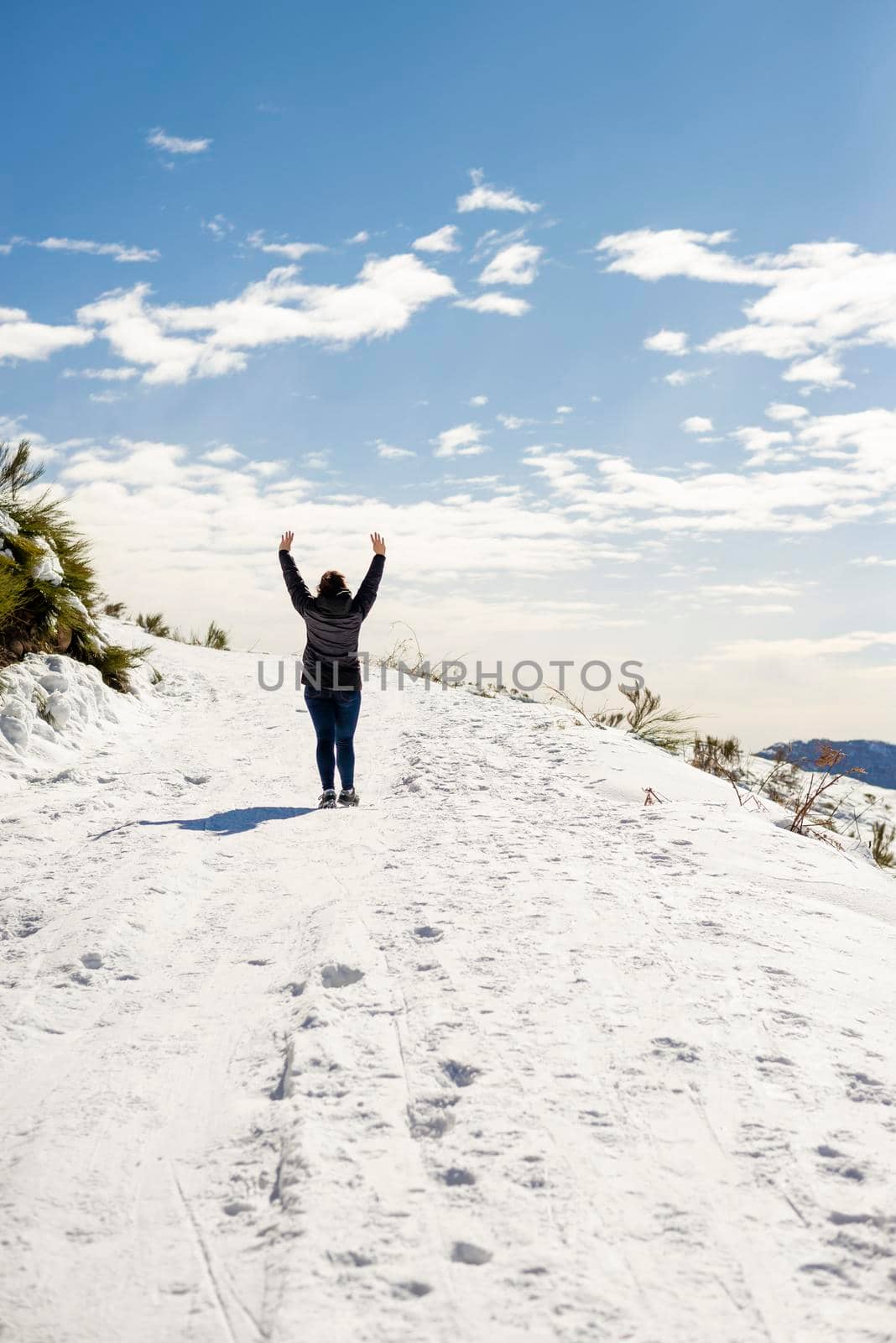 Young traveler woman standing on snowed with arms raised by raferto1973