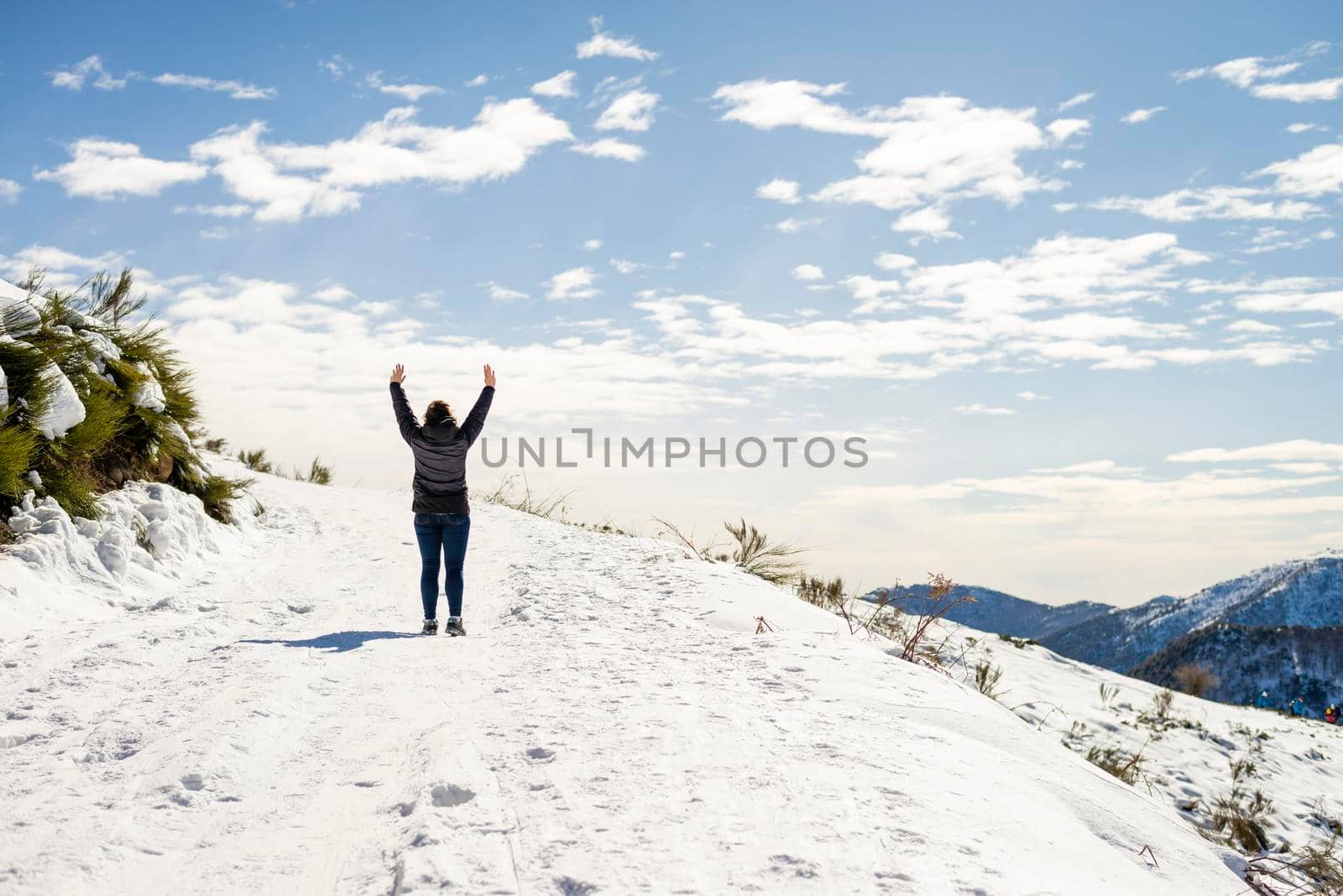 Young traveler woman standing on snowed with arms raised by raferto1973
