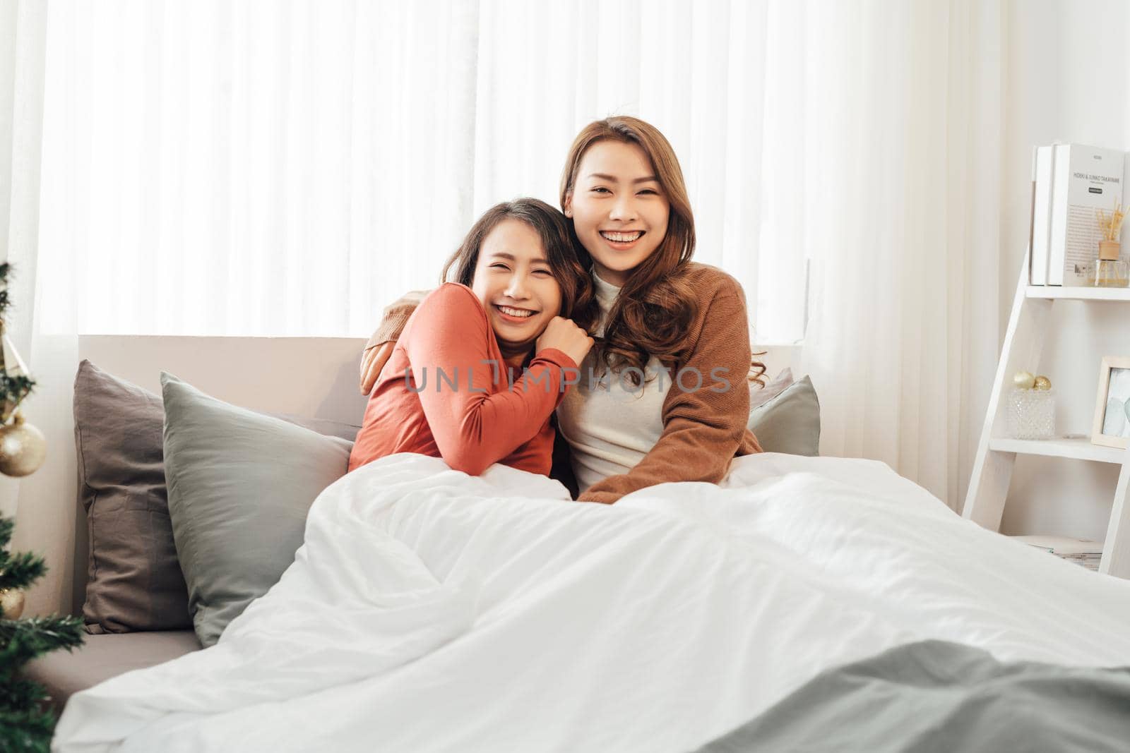 Two asian beautiful women or lesbian laying down and playing together on cozy bed. by makidotvn