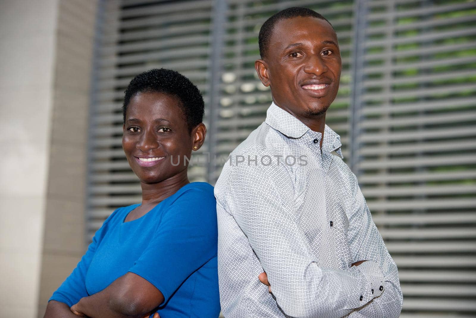 young couple standing crossed arms watching the camera smiling.