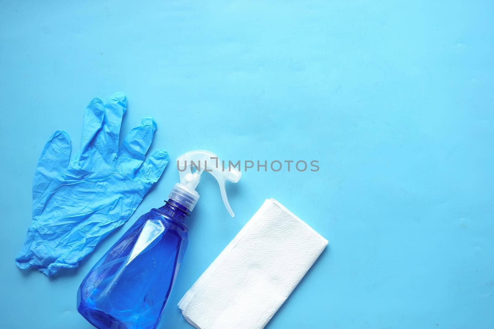 cleaning paper, bottle and hand gloves on blue .