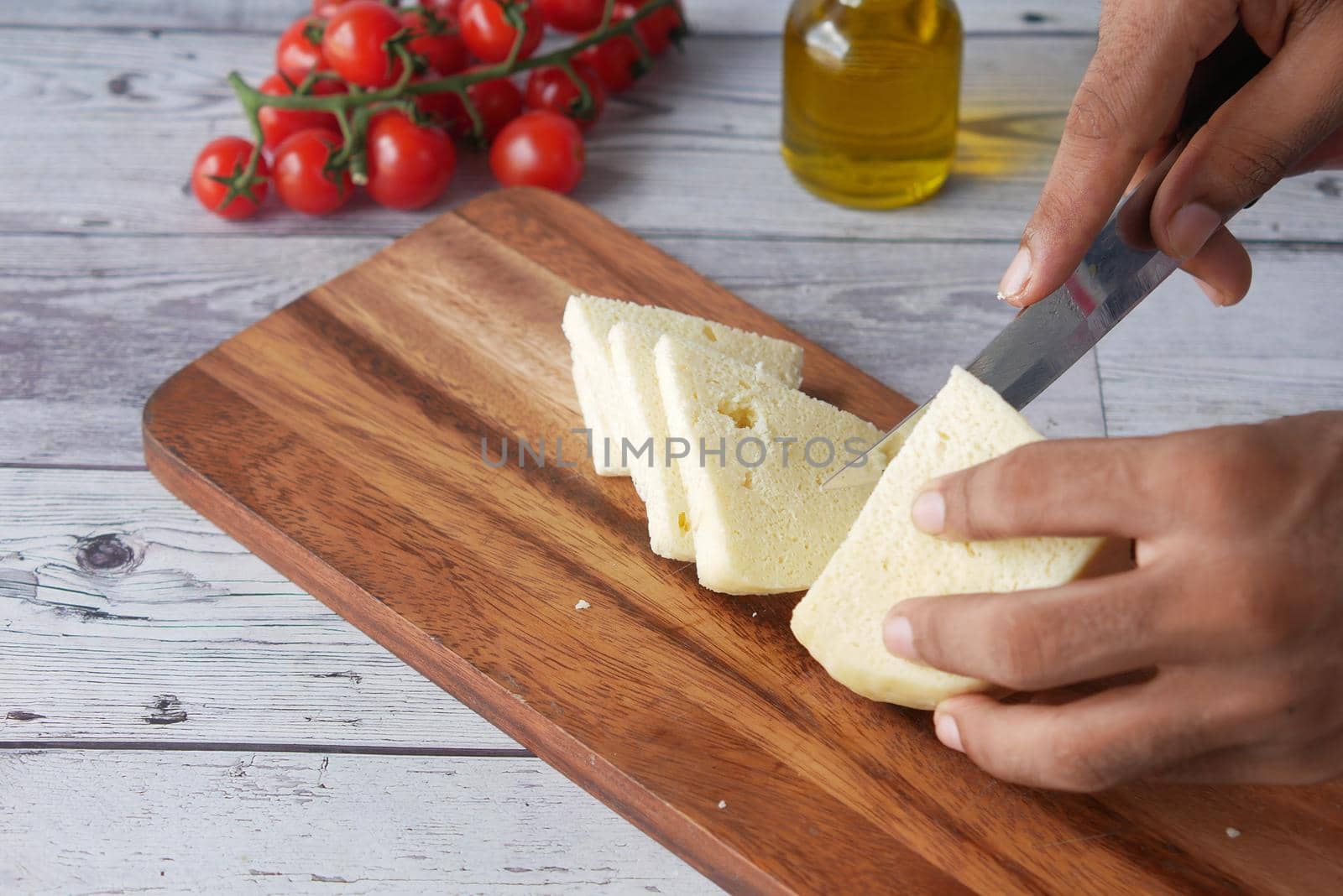 close up of man's hand cutting cheese on a chopping board by towfiq007