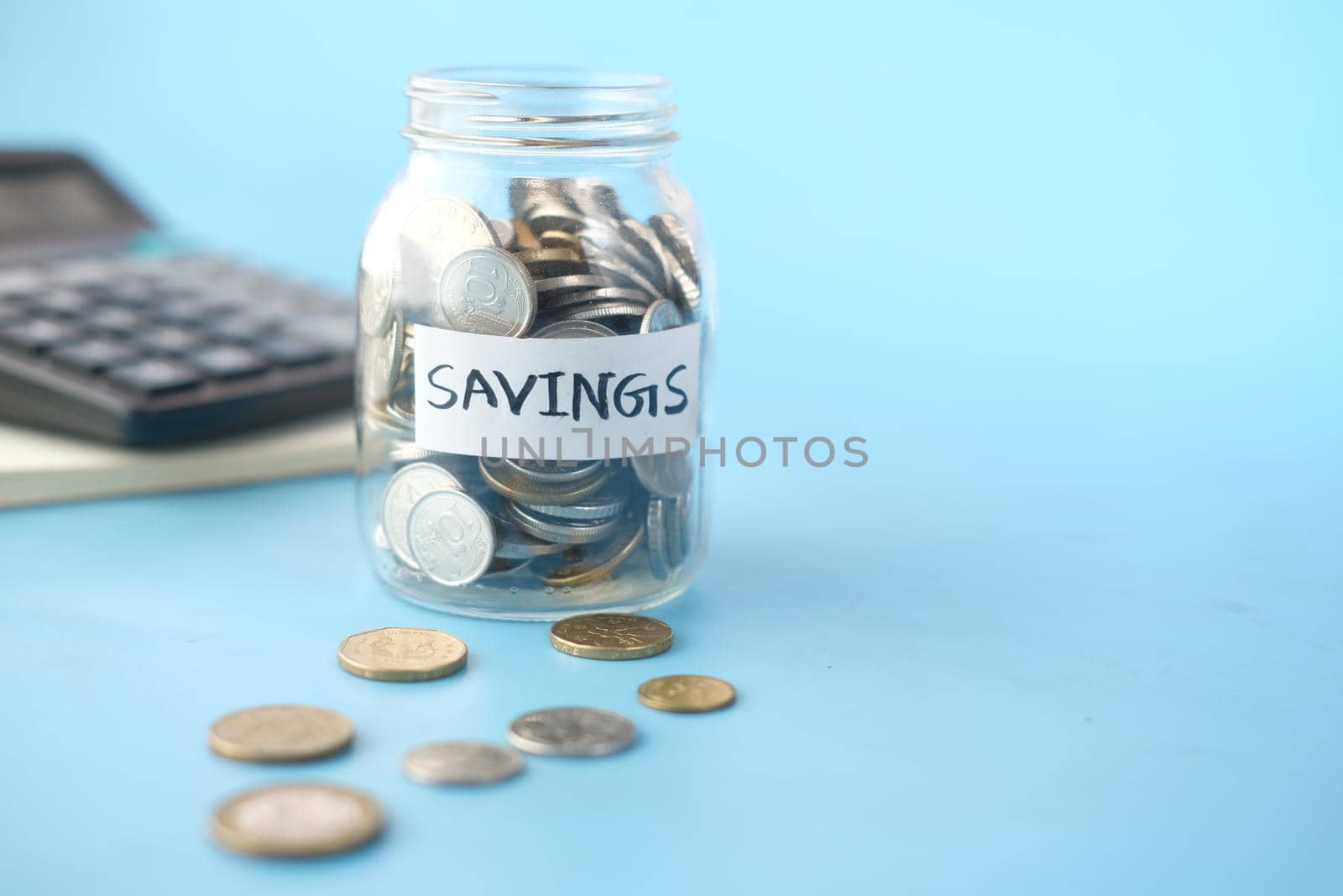 saving coins jar and calculator on table .