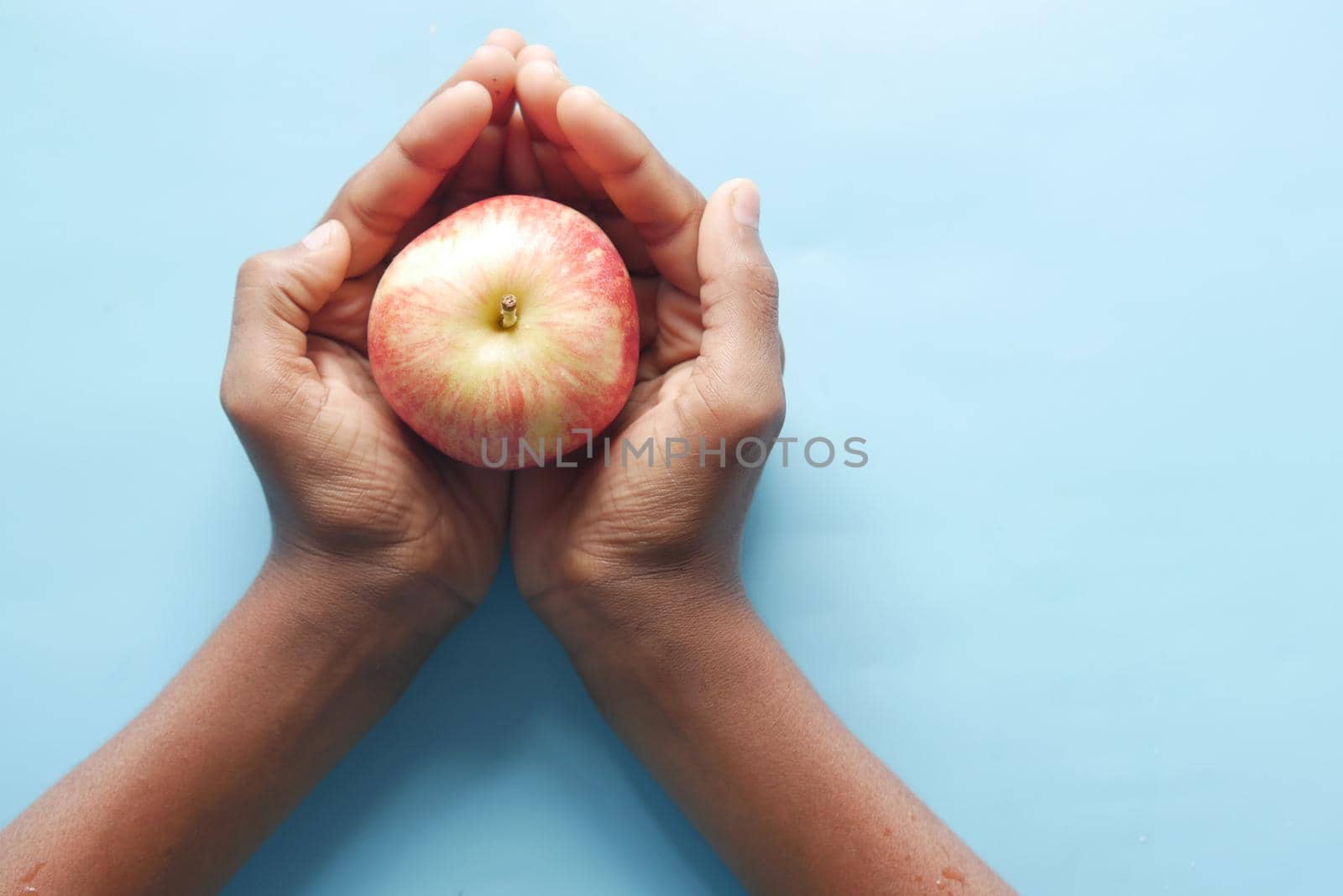 child boy hand hold a apple on blue background by towfiq007