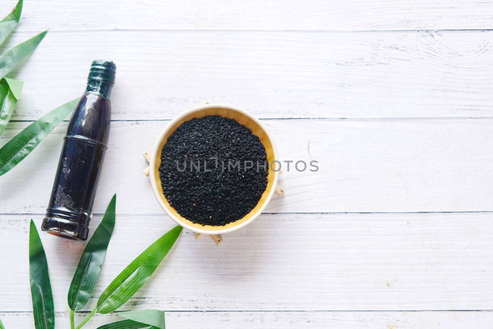 Black Cumin in a container with oil in a jar on table