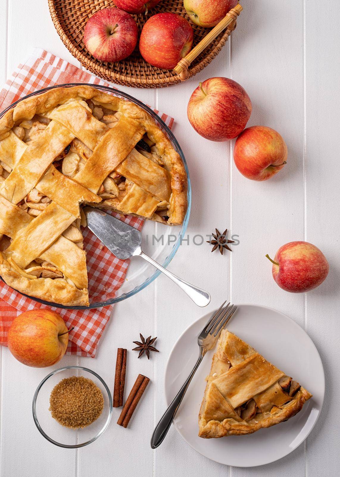 Autumn foods. Top view of homemade apple pie on white wooden table, decorated with apples, sugar and tablecloth