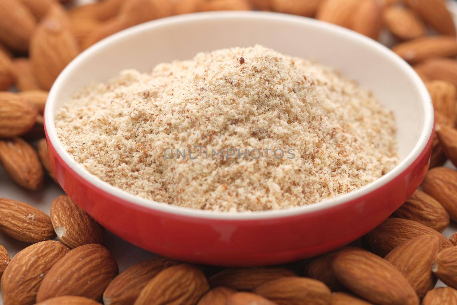 almond powder in a container with almond nut on table .
