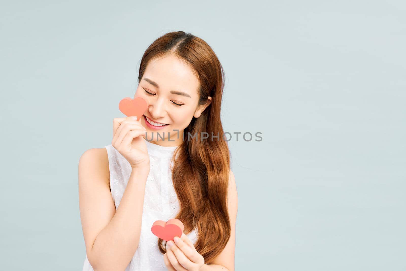 Beautiful woman holding paper hearts on white background