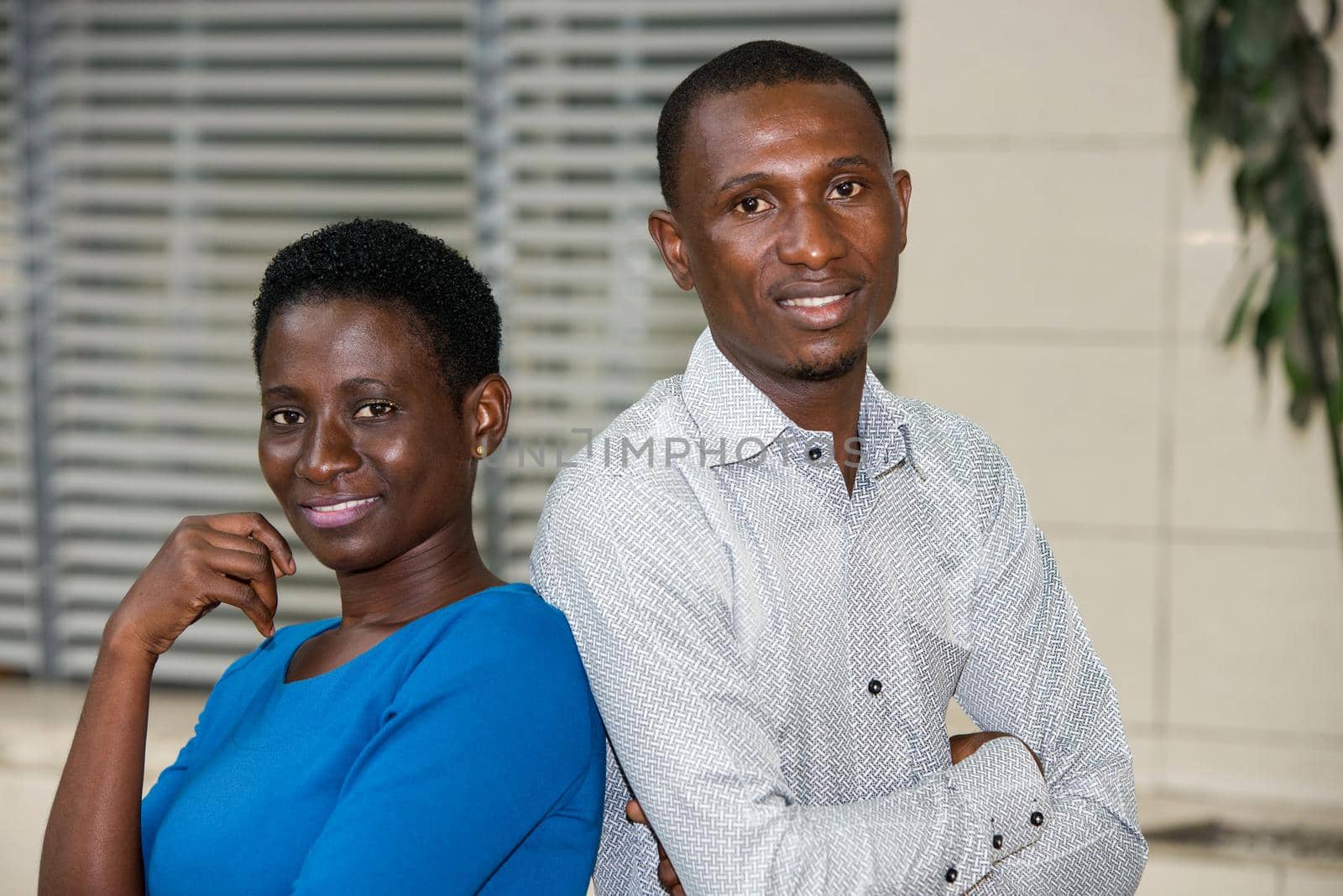 young couple standing staring at camera smiling.