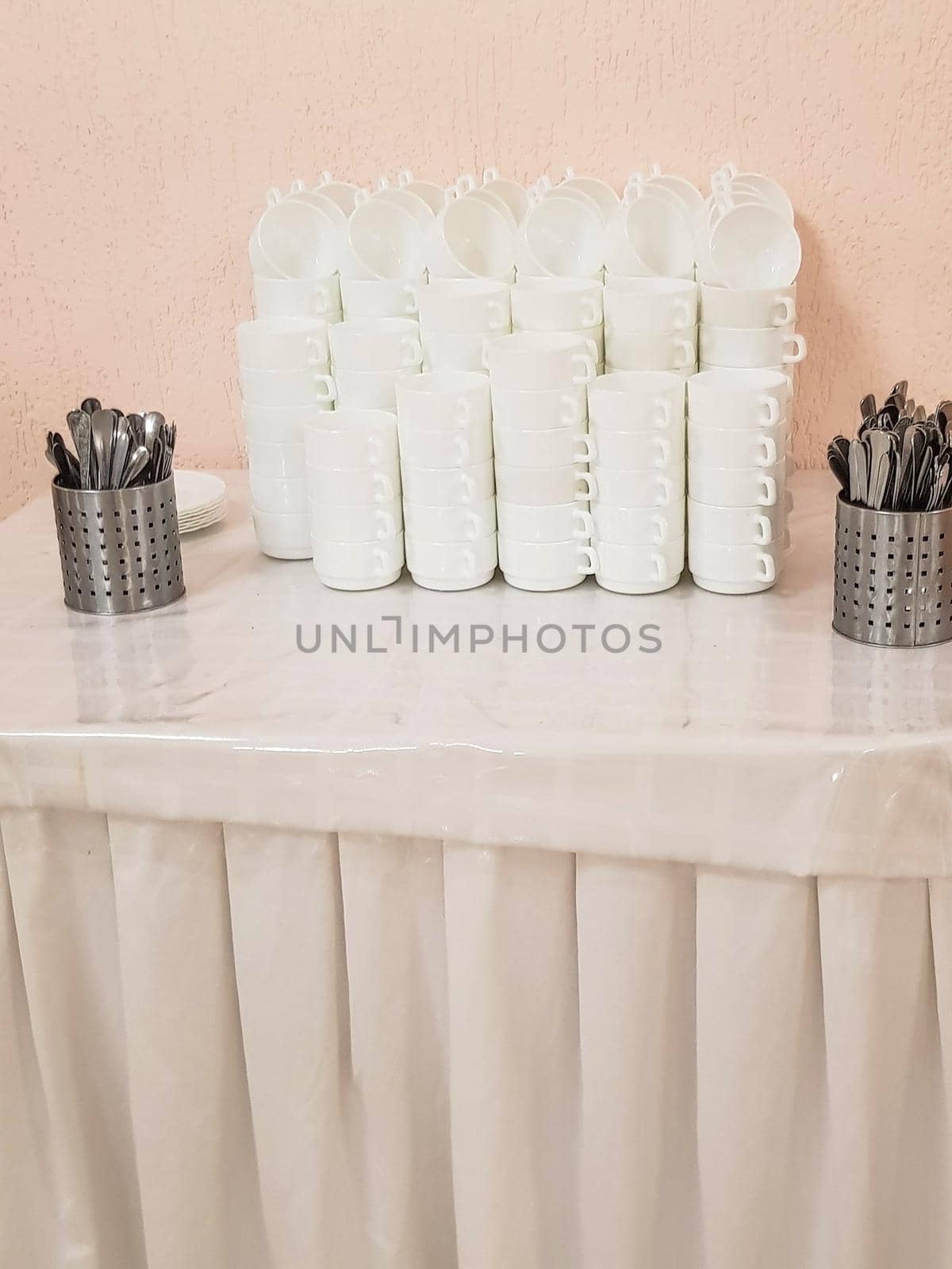 White clean empty soup plates in a stack and cutlery on the table, service in the hotel cafe.